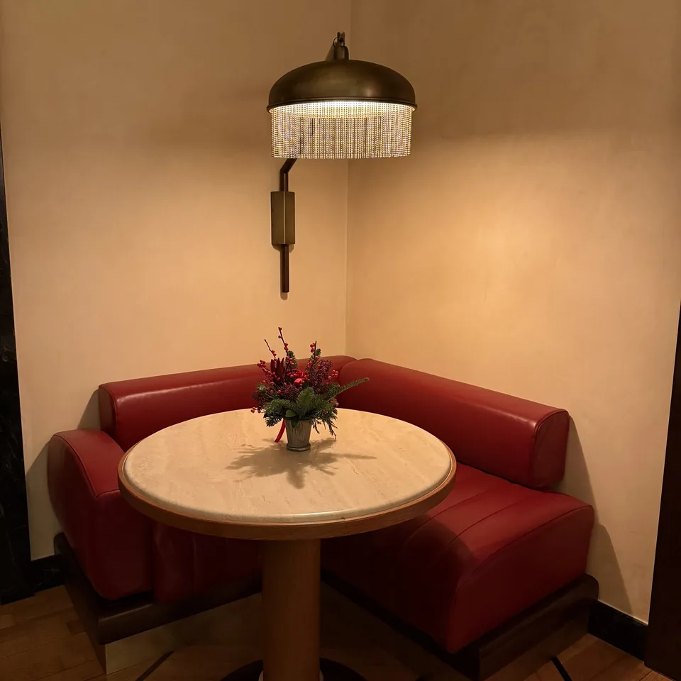 A red velvet banquette around a small round table in a corner