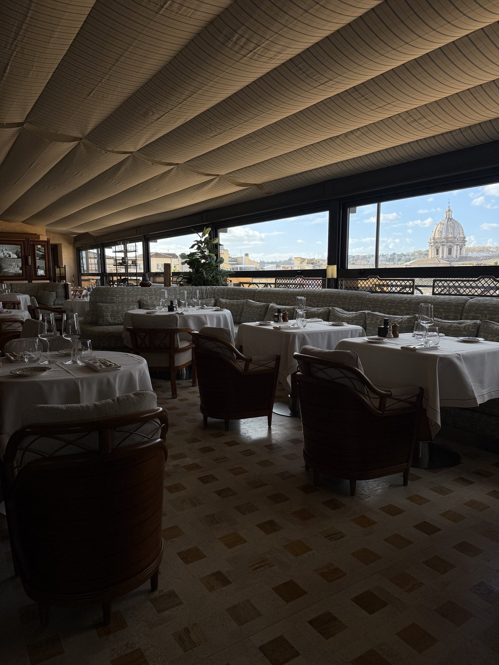 The rooftop dining room with tables laid and the dome of St Peter's through the glass