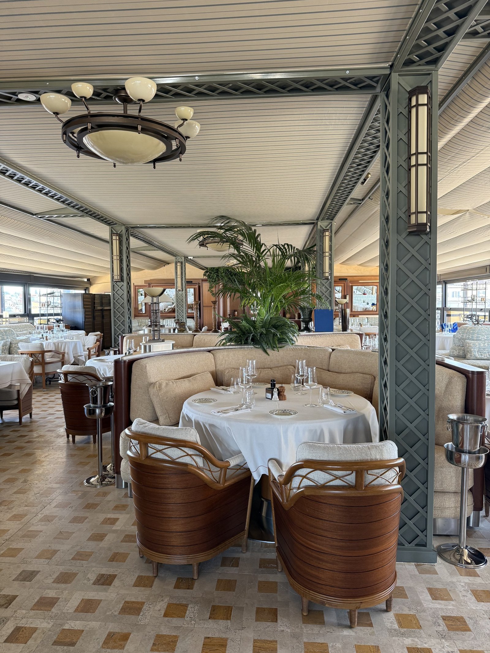 Tables laid for lunch on the rooftop restaurant under its awning with the Roman sky beyond