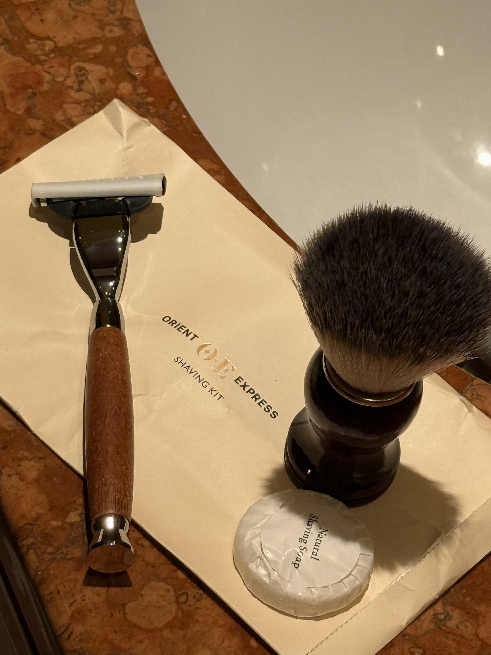 A razor and a shaving brush laid out on an Orient Express napkin