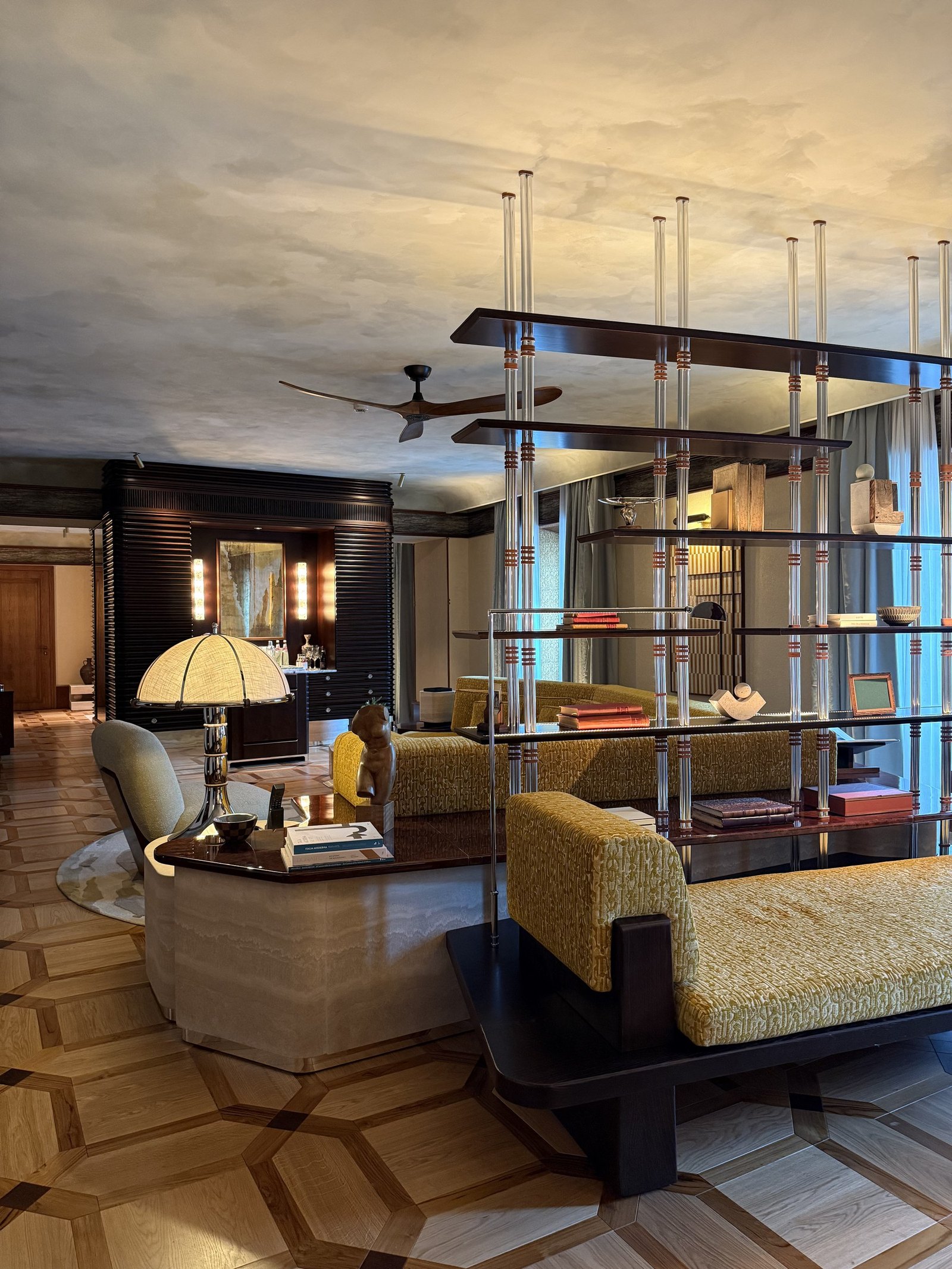 The living area of a Junior Suite with a vertical screen, green sofa and ceiling fan