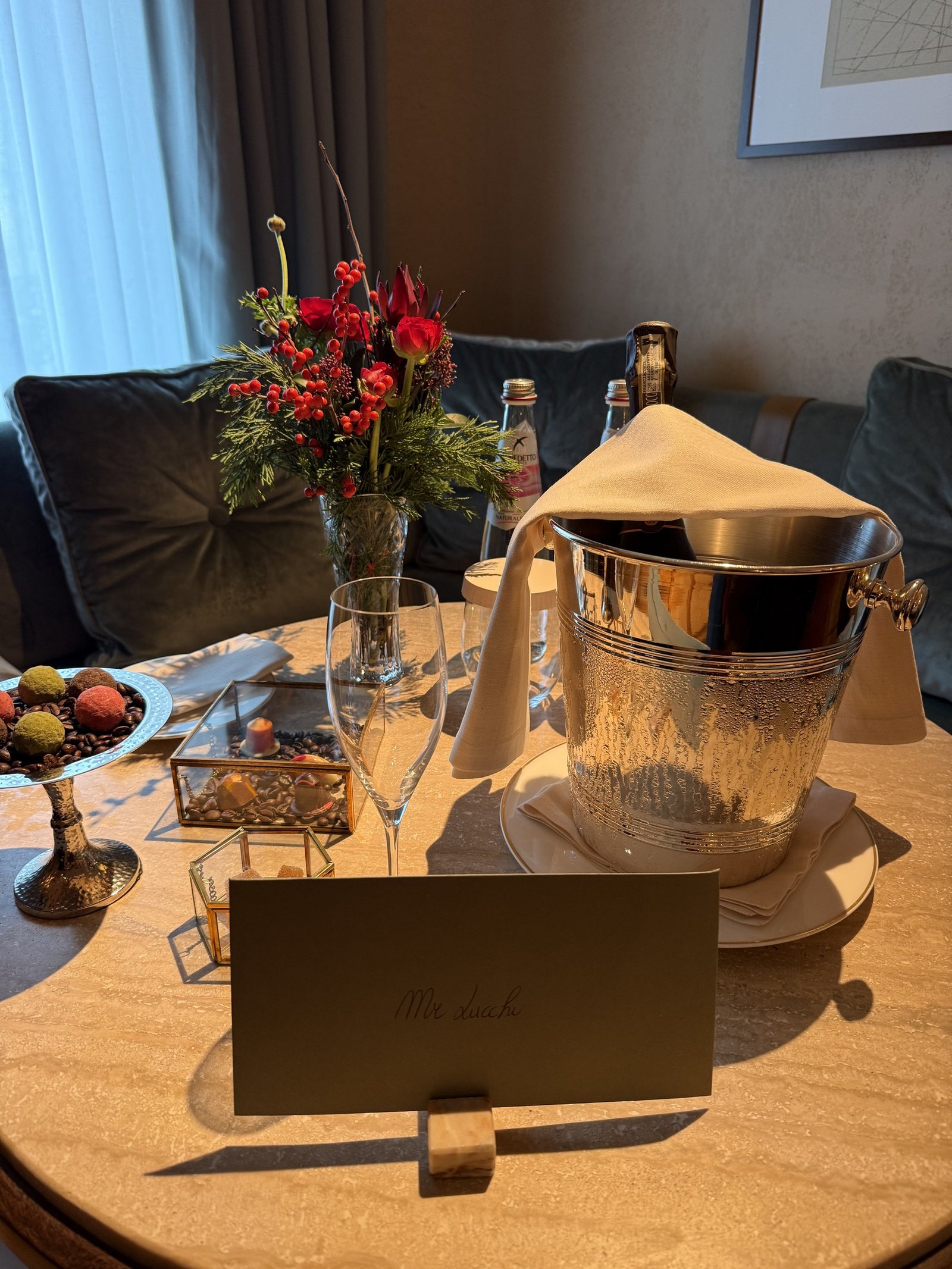 A welcome table with flowers, an ice bucket, chocolates and a handwritten card