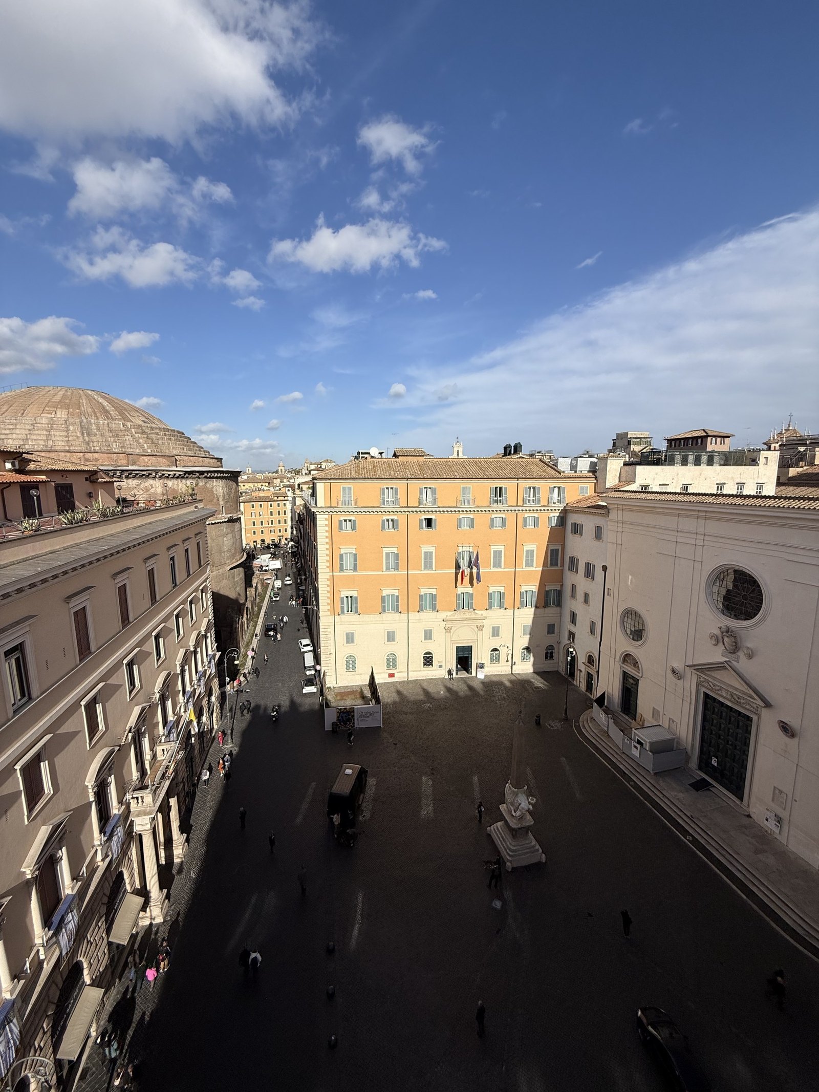 The view from a hotel window down onto a Roman square under a blue sky