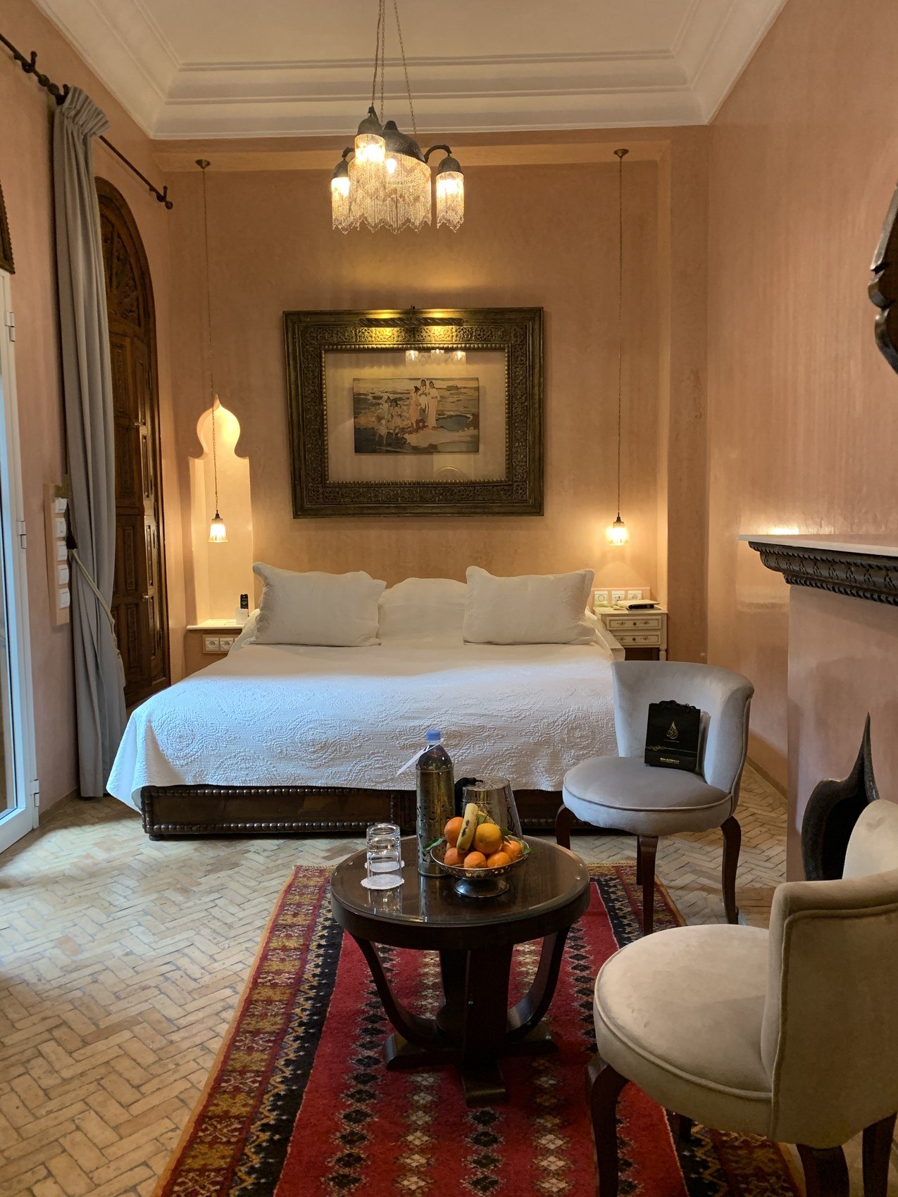 A suite at La Sultana with a wide bed, a fireplace, a framed print and a red patterned rug