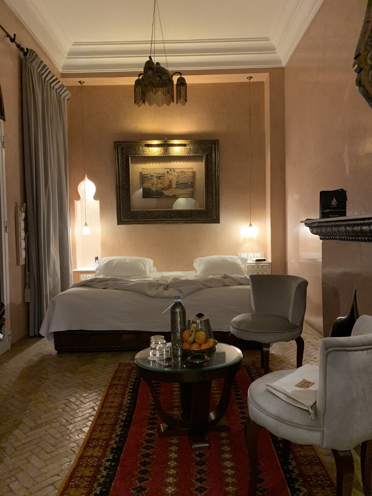 A bed at La Sultana between carved timber screens with lanterns hanging low on either side