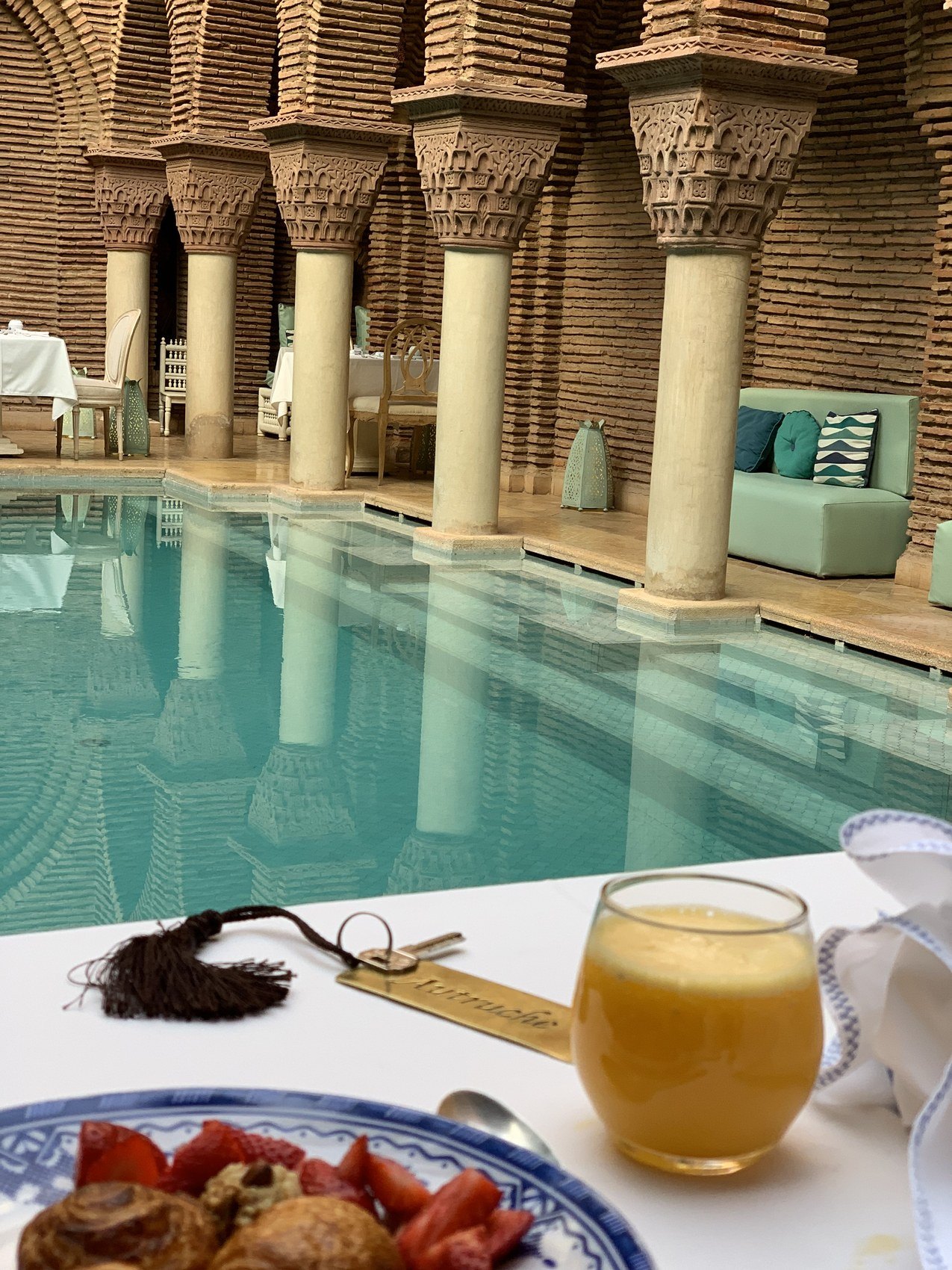 A breakfast of pastries and orange juice laid on a white cloth beside the pool at La Sultana