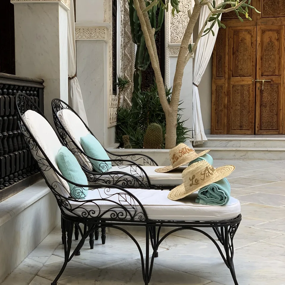 Wrought iron daybeds with pale cushions in a courtyard at La Sultana under an old olive tree