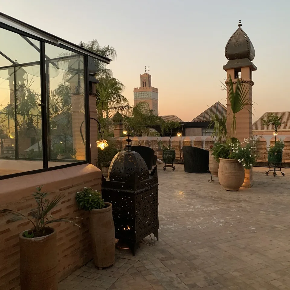 The glazed pavilion on the roof terrace at La Sultana at dusk with the Koutoubia minaret behind