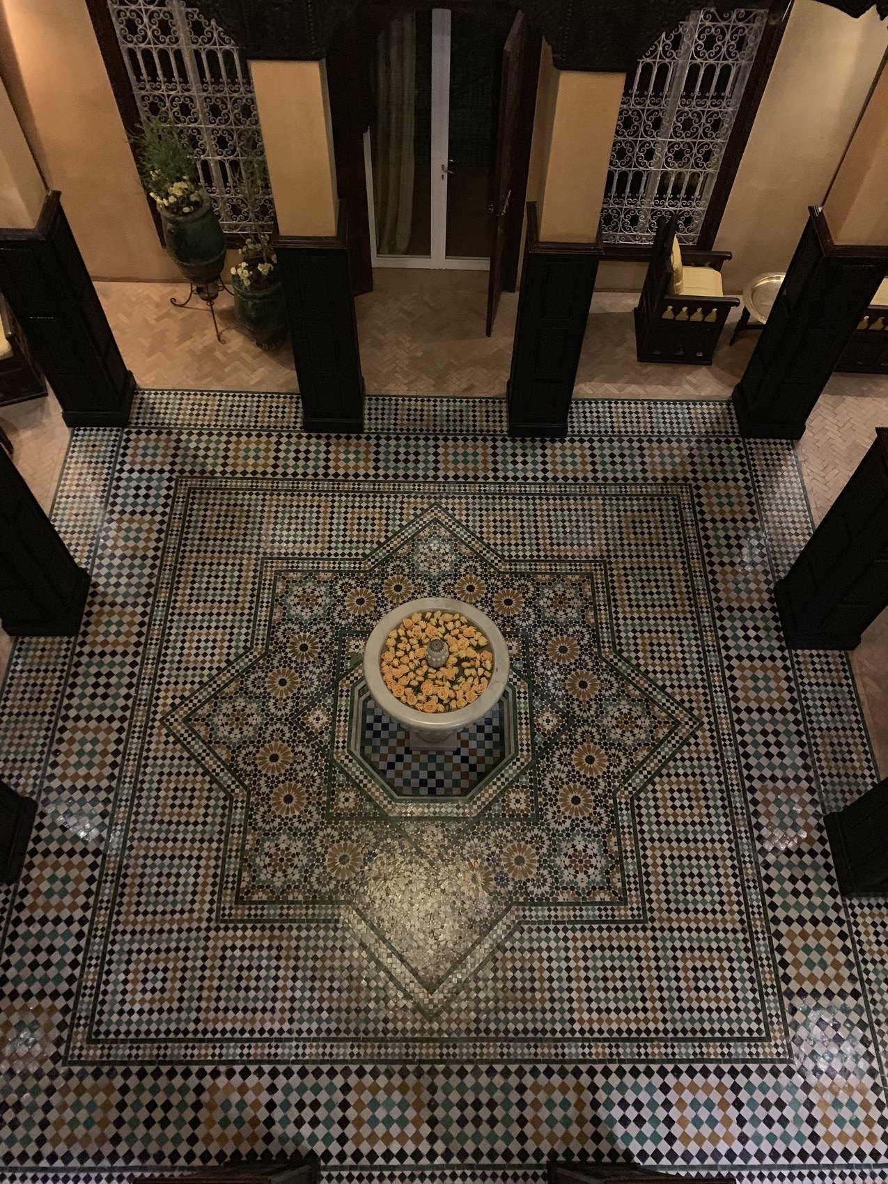Looking down onto a courtyard floor at La Sultana laid in a black and white zellige star around a stone basin