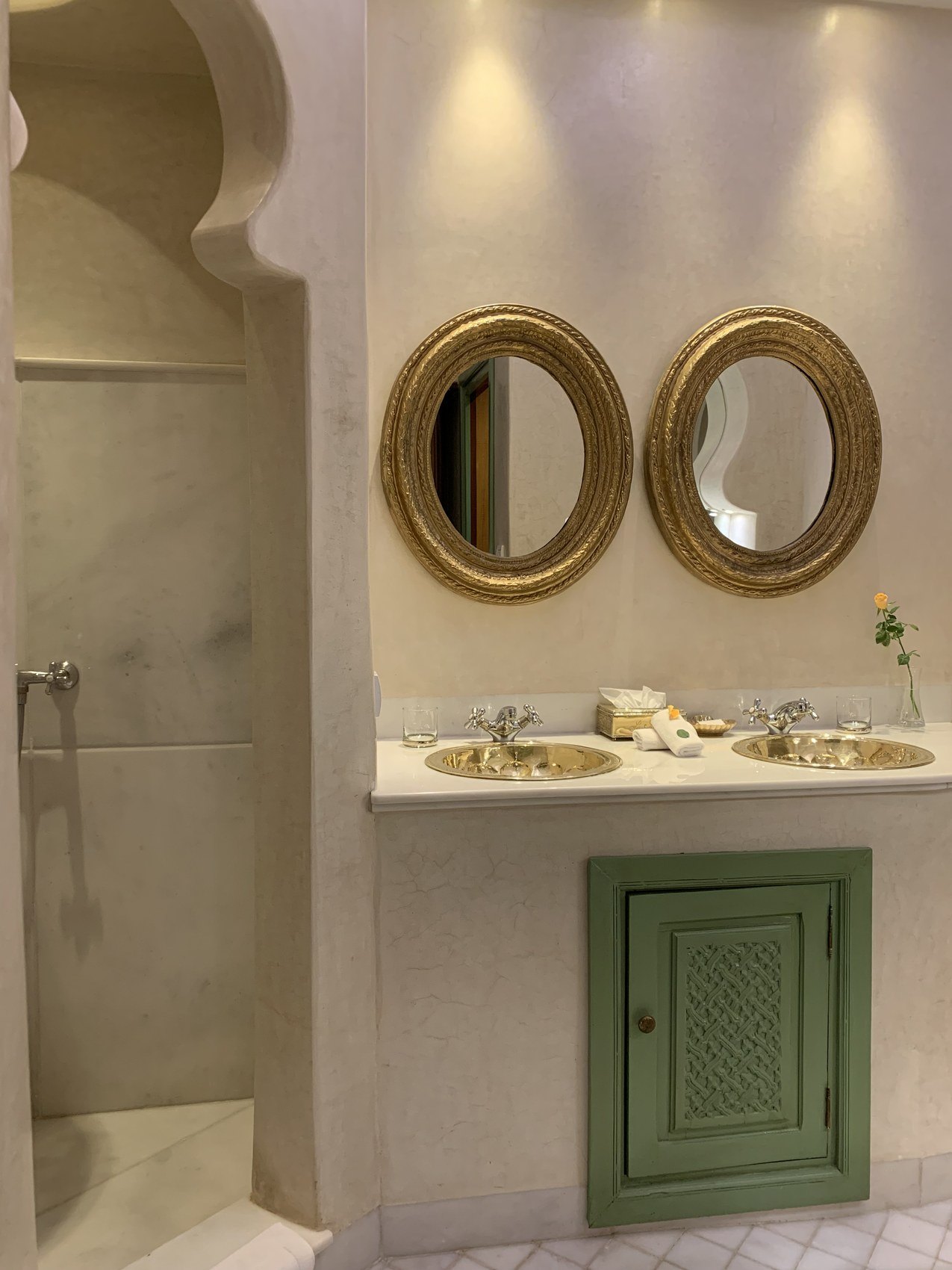 Two gilt oval mirrors above a stone basin at La Sultana with a pale green cabinet below