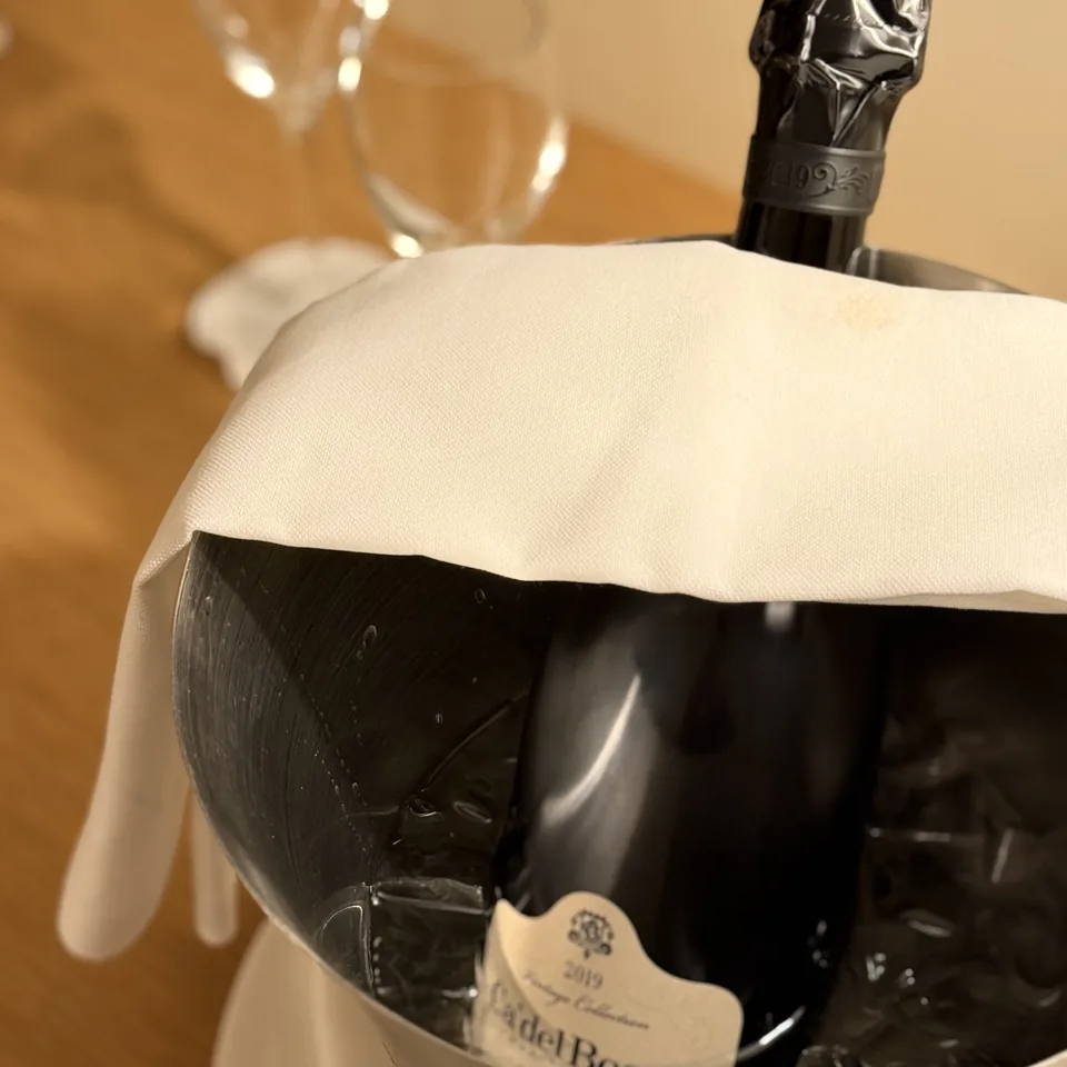 A bottle of Franciacorta in an ice bucket with two glasses behind it