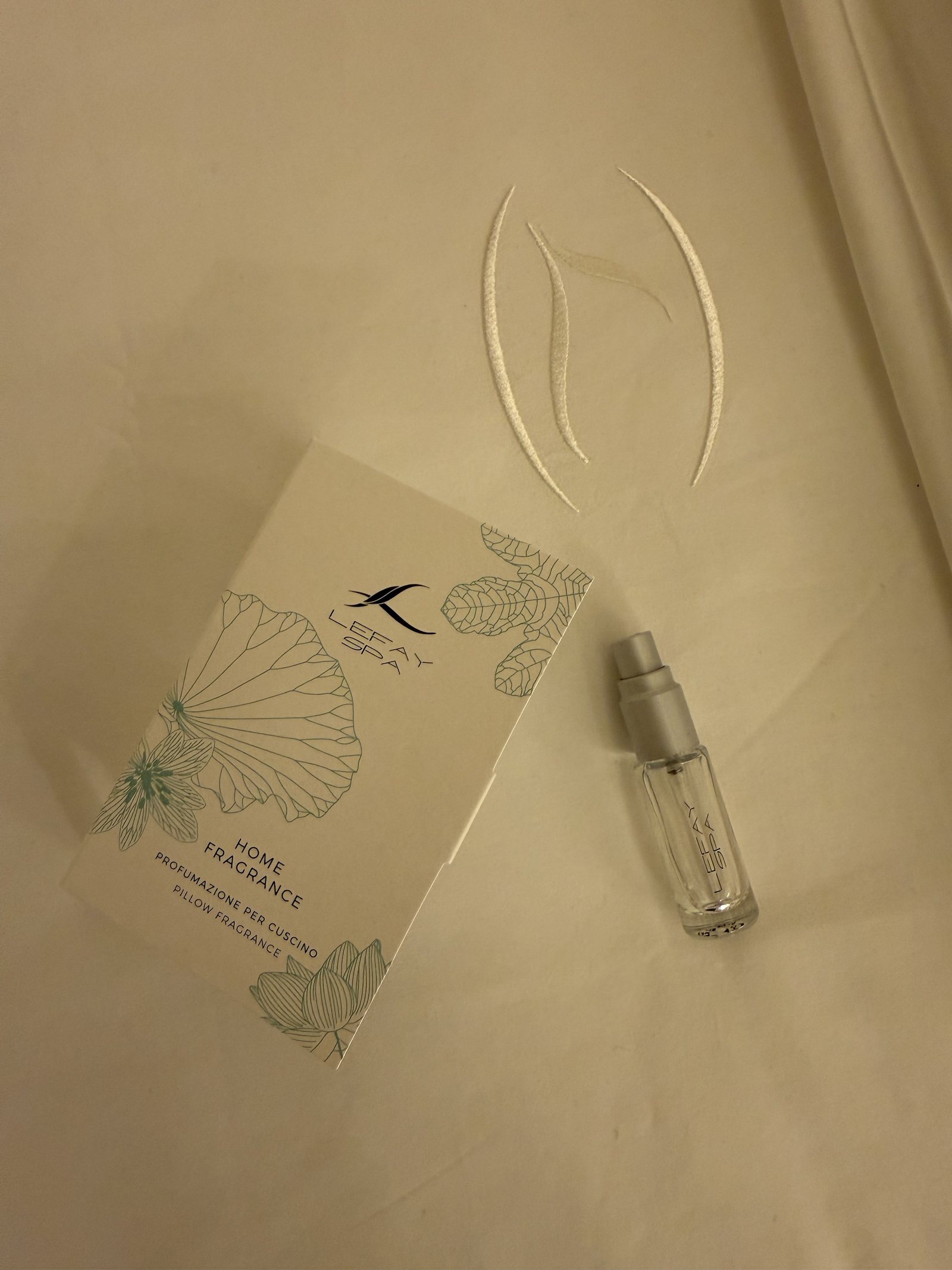 A card for Lefay home fragrance beside a small glass bottle on a cream surface