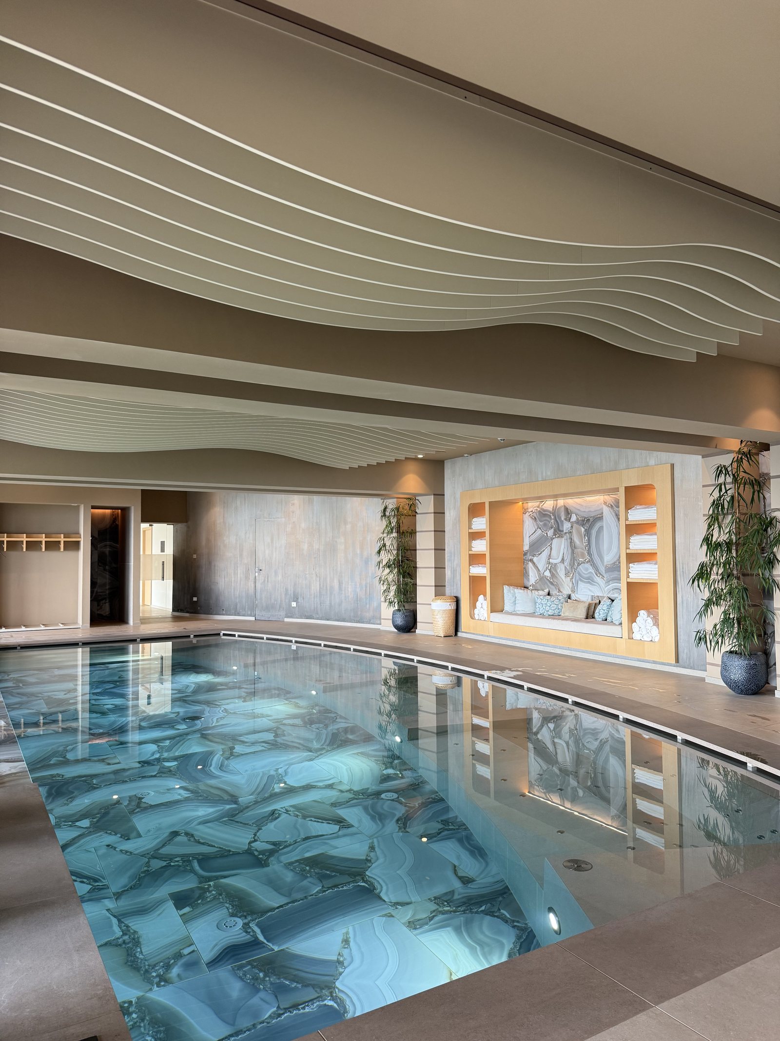 The same pool from the other end, with loungers along the glass and the hillside outside