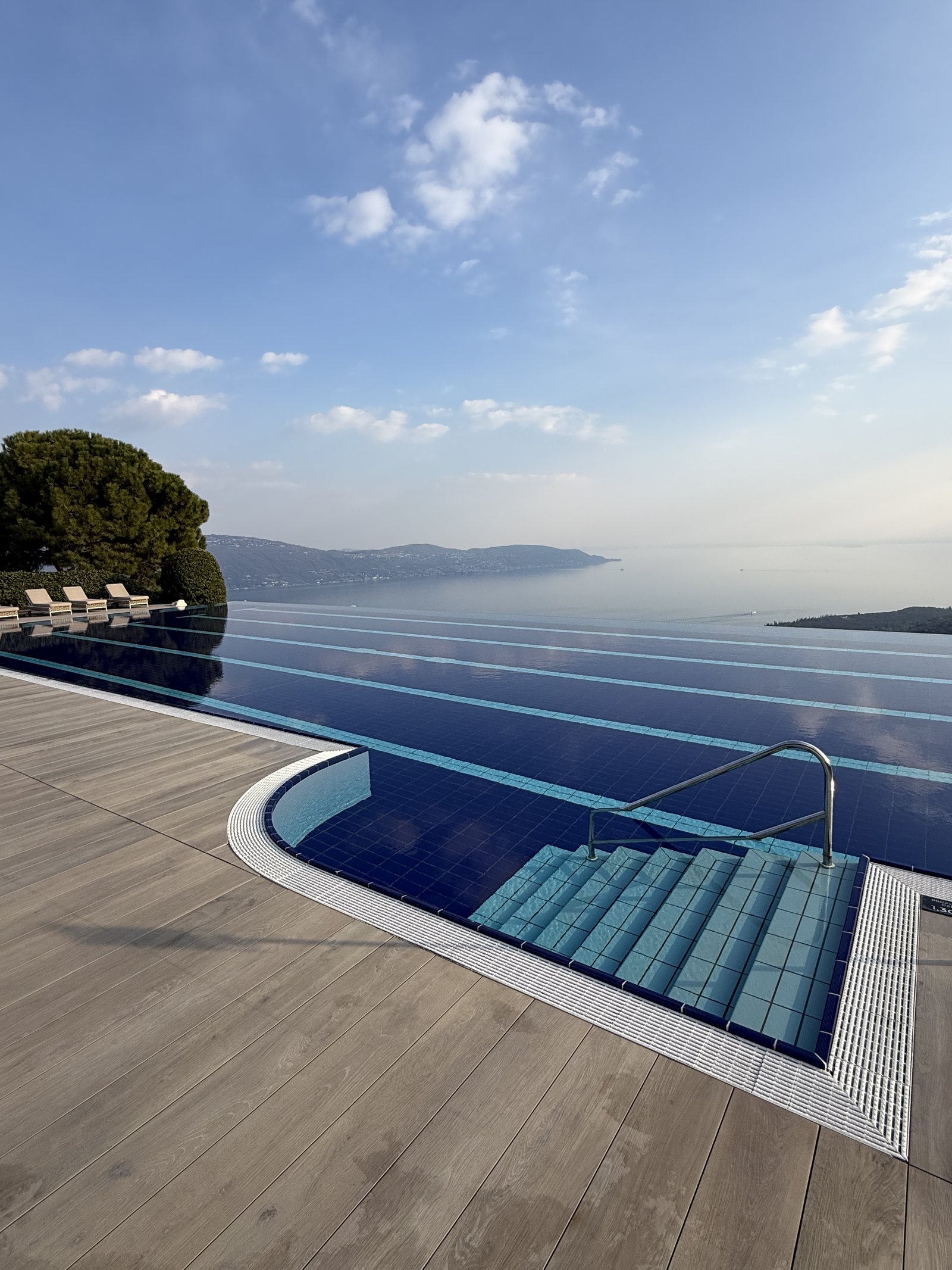 The heated outdoor pool at Lefay, its blue tiles running to an edge that disappears into Lake Garda behind it