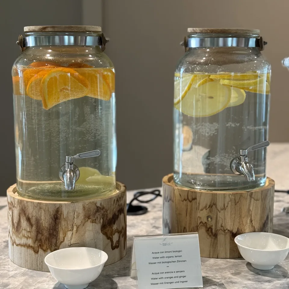 Two glass dispensers of water infused with orange and lemon on sections of tree trunk