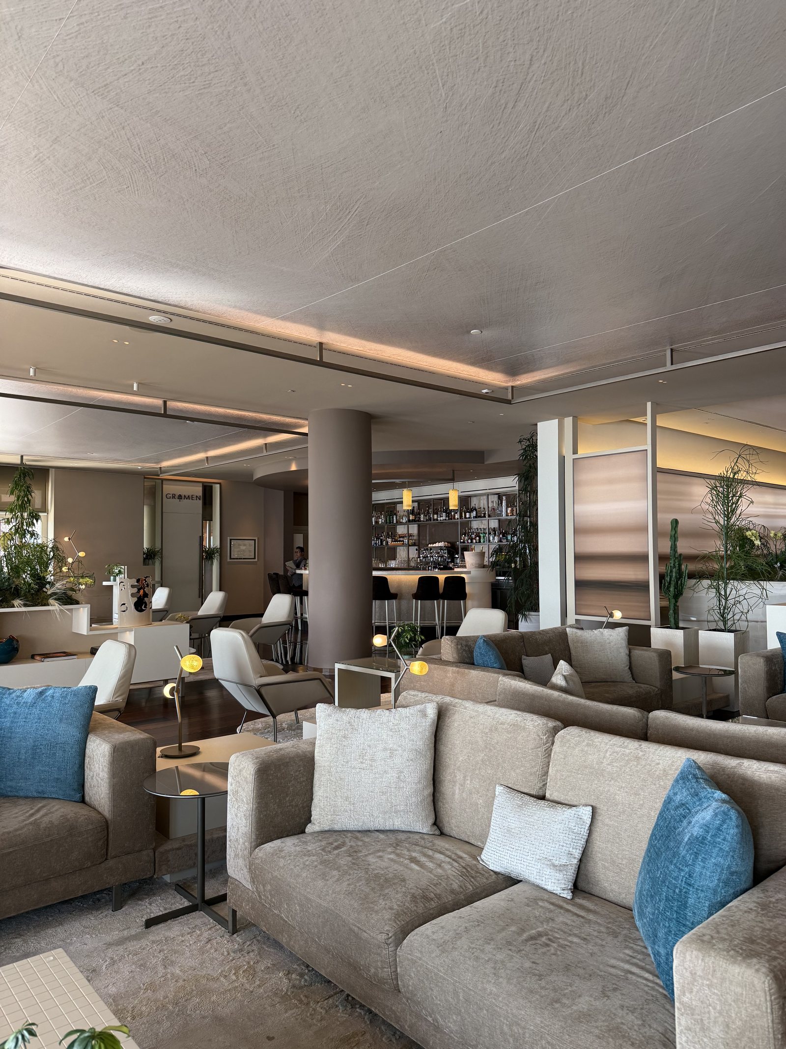 A sitting room with pale sofas and armchairs, tall windows and a view to the terrace