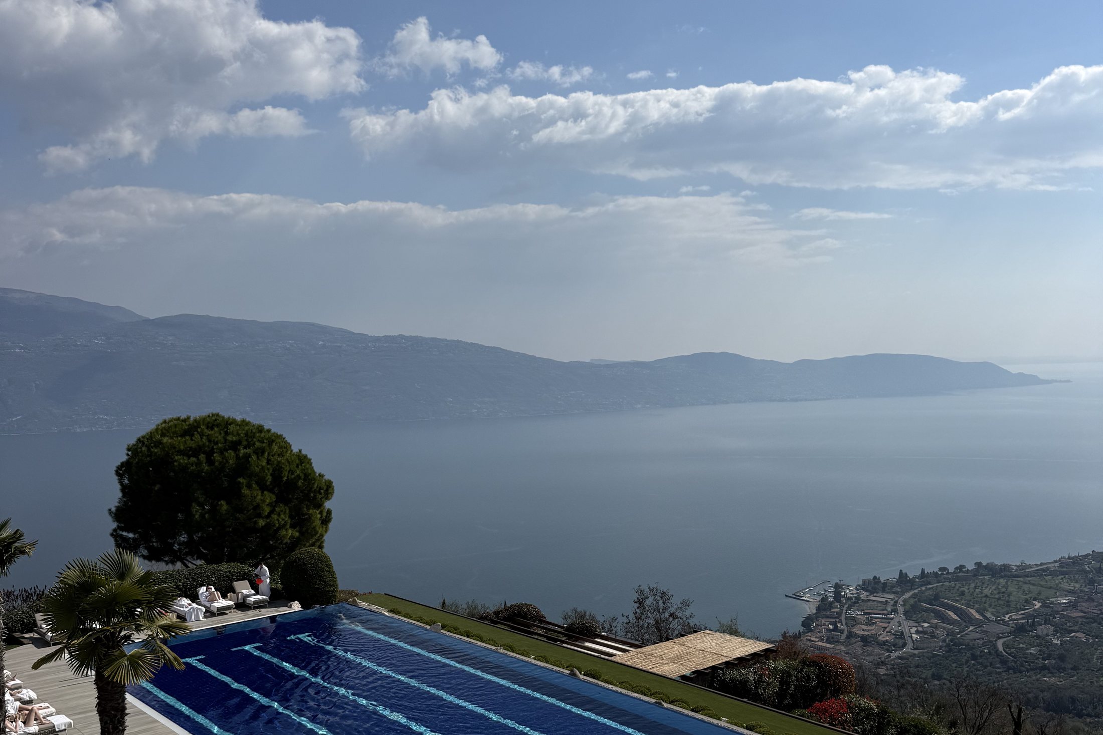 The long heated outdoor pool seen from above, with Lake Garda and the far shore behind it