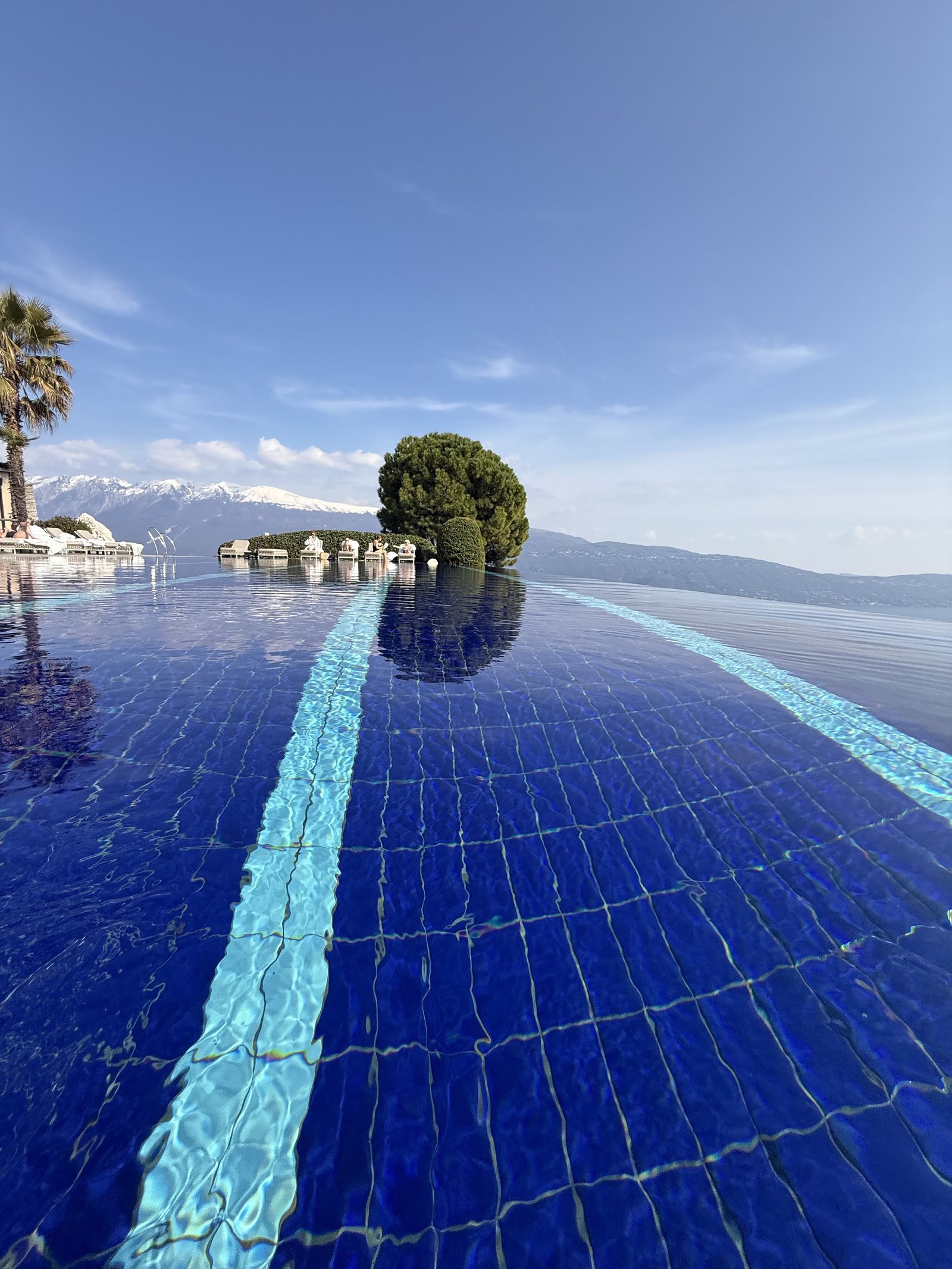 The rim of the infinity pool with water running over it, the lake directly beyond