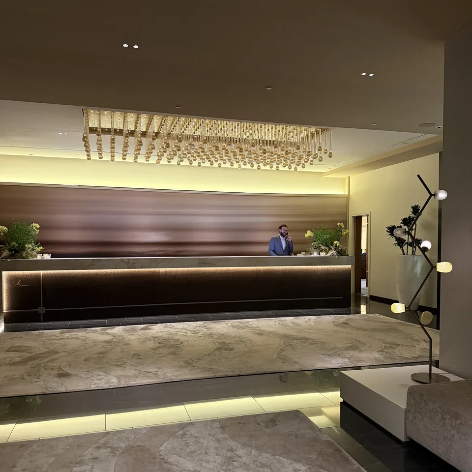 The reception desk in the evening under a long chandelier, with a member of staff behind it