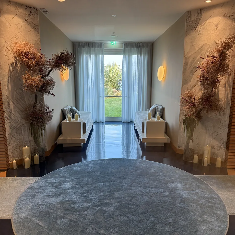 A round grey stone table on a dark floor, between dried flower arrangements and candles
