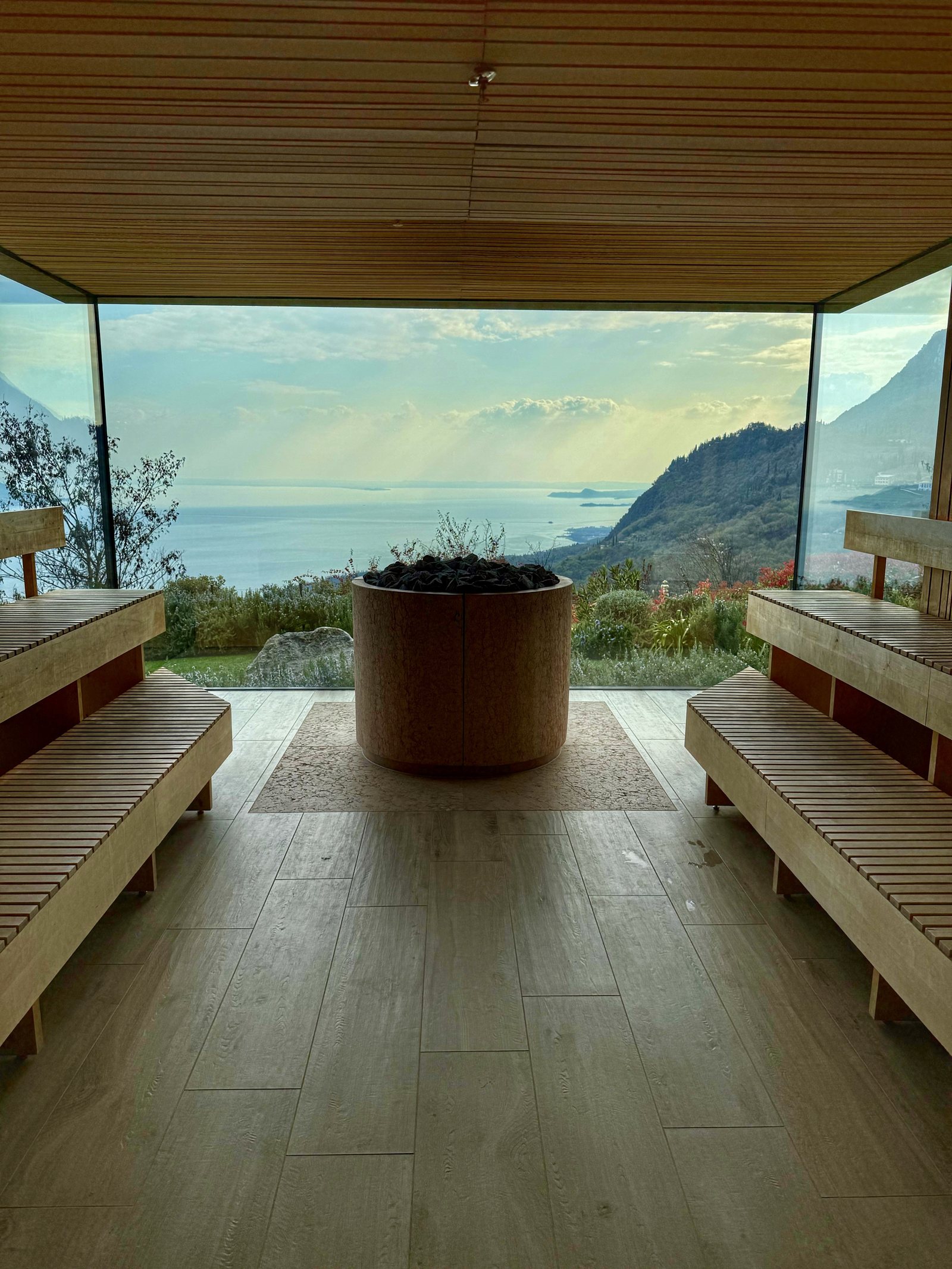 The inside of a timber sauna with benches on both sides and a window filling the end wall