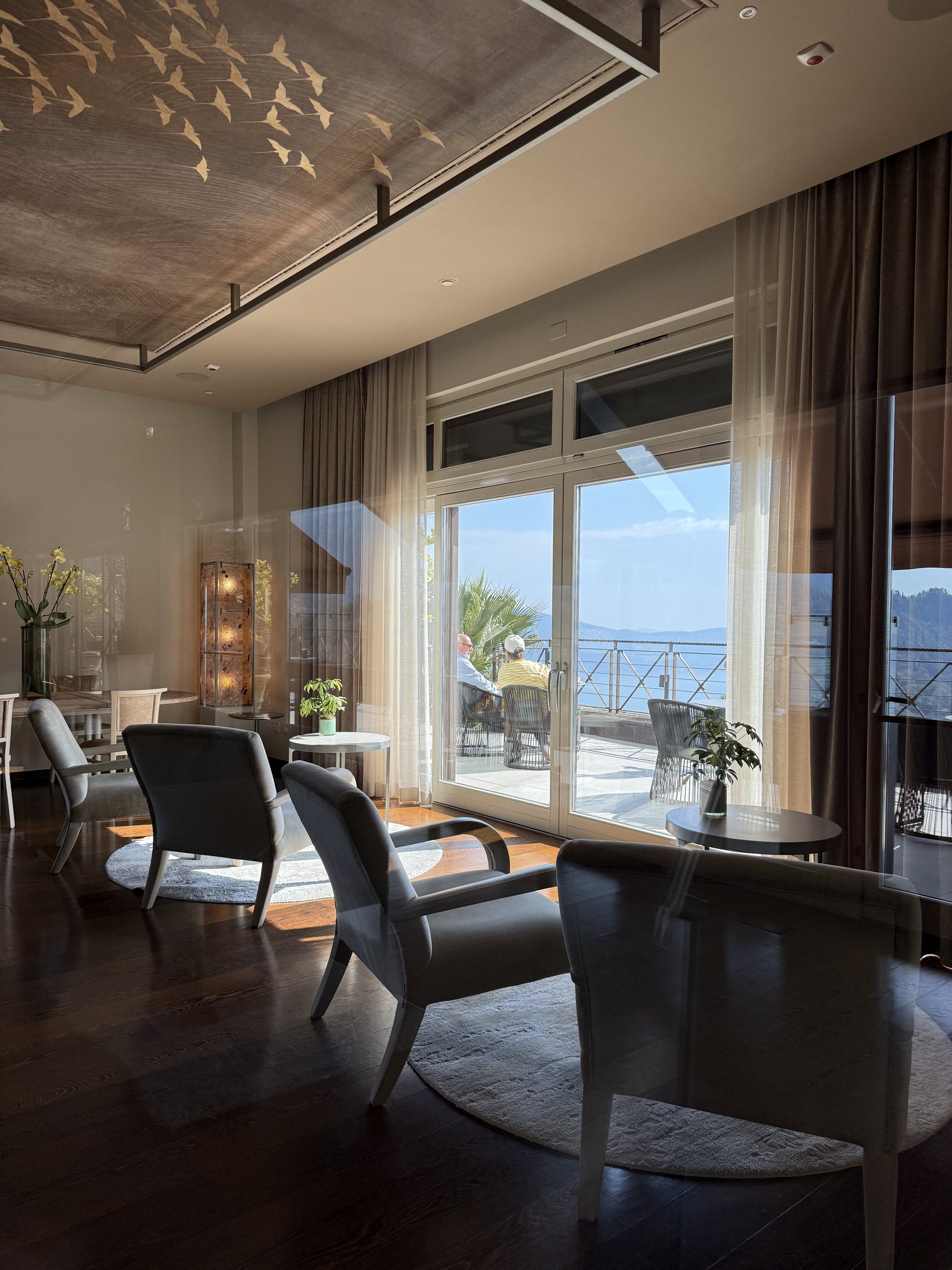 A sitting area with armchairs and a low table in front of floor-to-ceiling windows onto a terrace