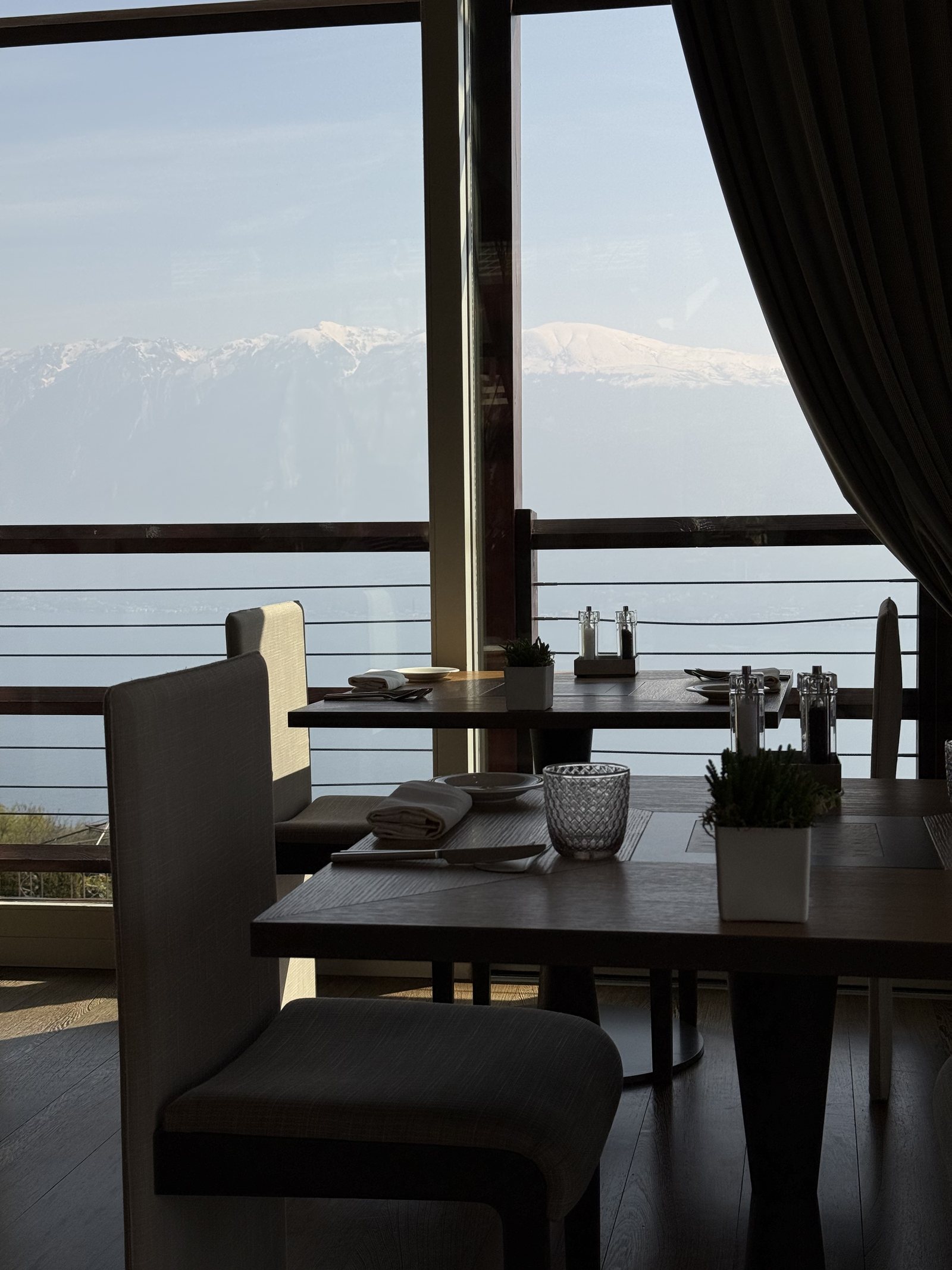 A table laid for two beside a floor-to-ceiling window with the lake and snow beyond
