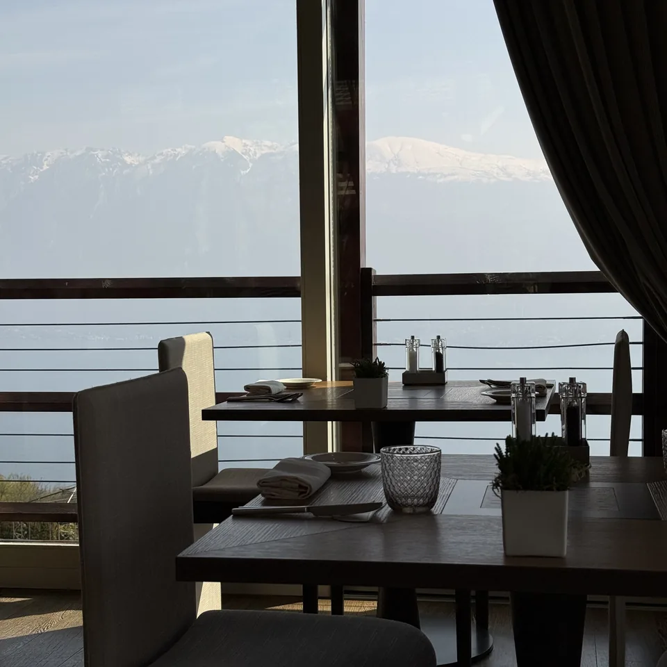 A table laid for two by a floor-to-ceiling window, with the snow on the far shore beyond
