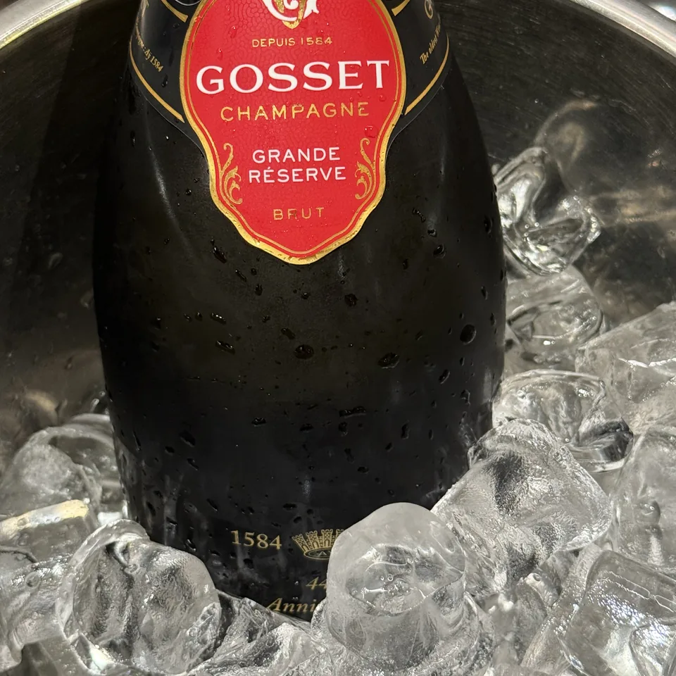 A bottle of Gosset Grande Reserve in a dark bucket of ice