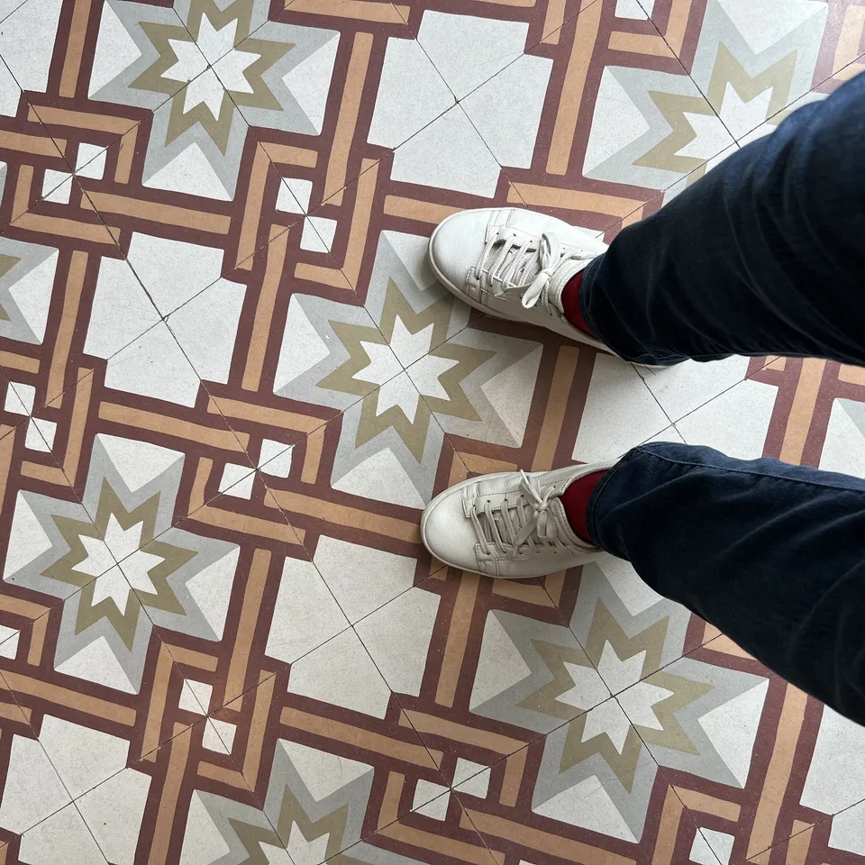 A pair of shoes from above on a geometric tiled floor in grey, white and ochre