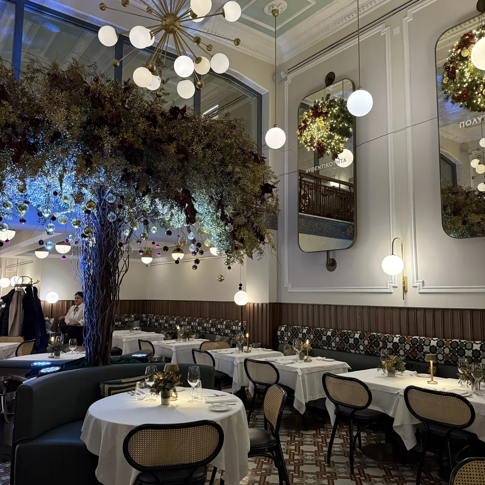 The dining room decorated for Christmas, a large blue-lit tree sculpture suspended over the laid tables