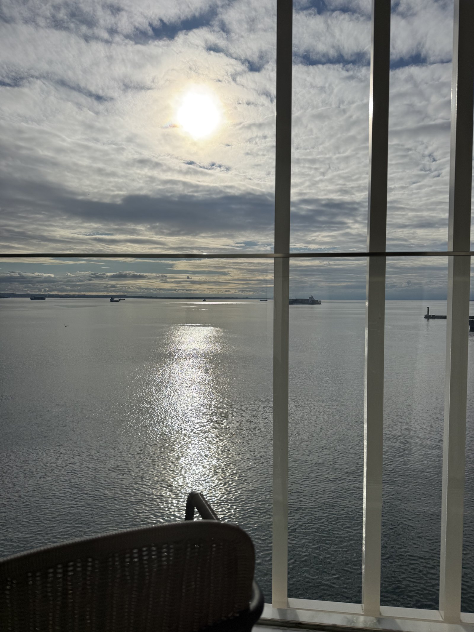 The sun low over the flat water of the Thermaic Gulf, seen through the vertical mullions of a window