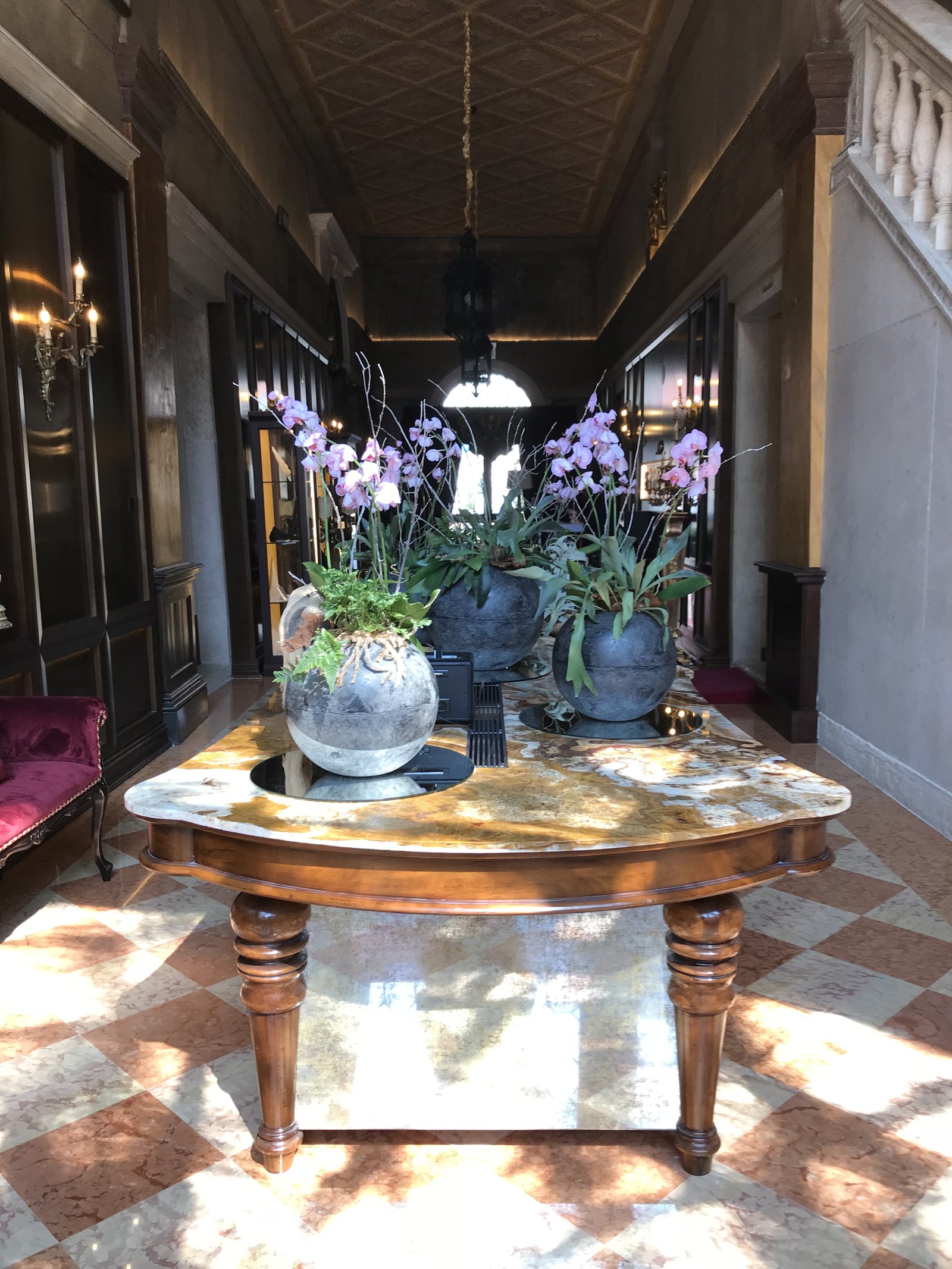 Two blue pots of orchids on a round wooden table in a corridor with lanterns overhead