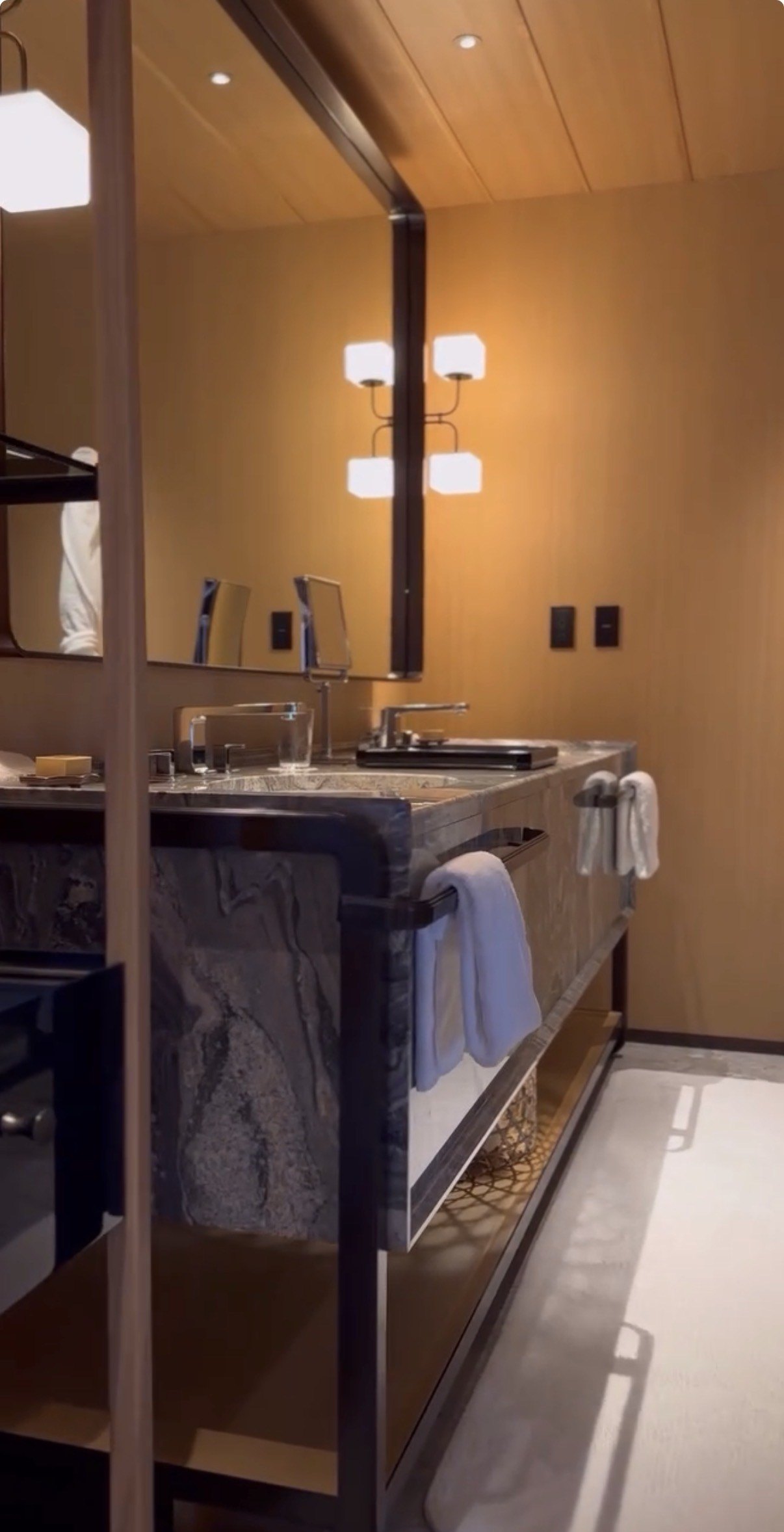 A bathroom in timber and stone with a long mirror and a deep tub