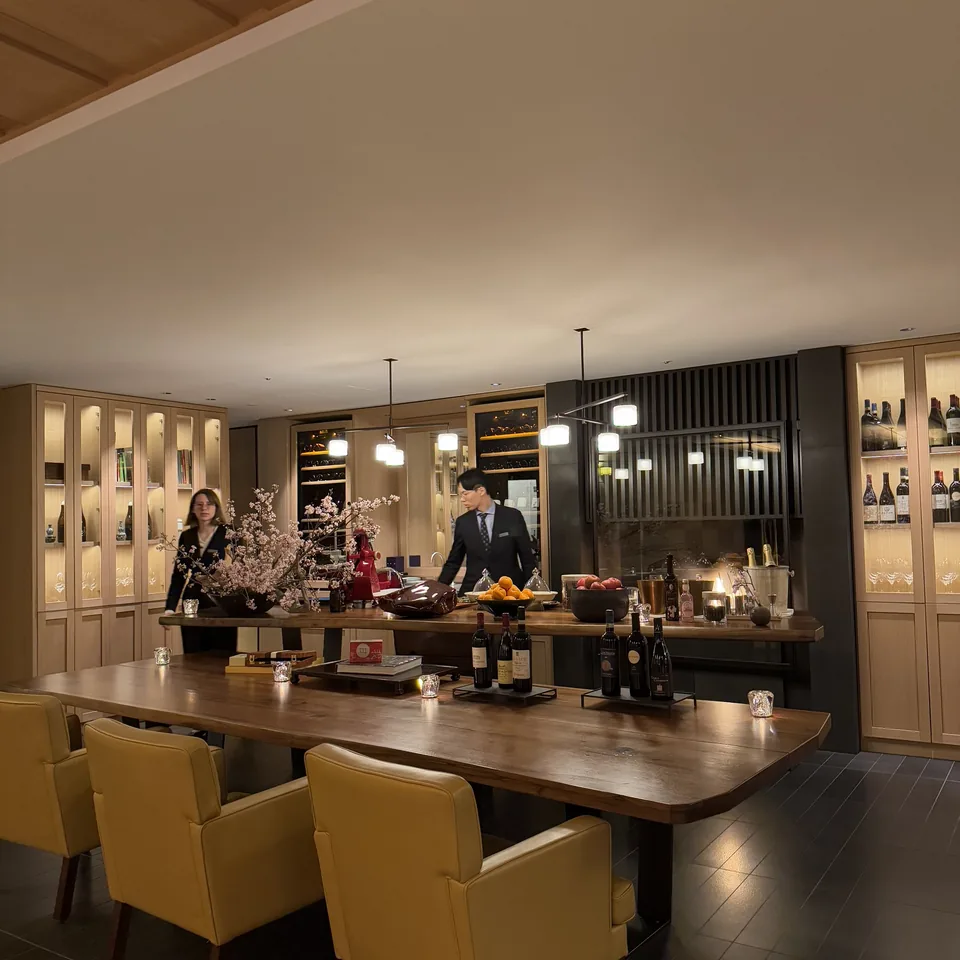 A long table set in a room lined with bottles