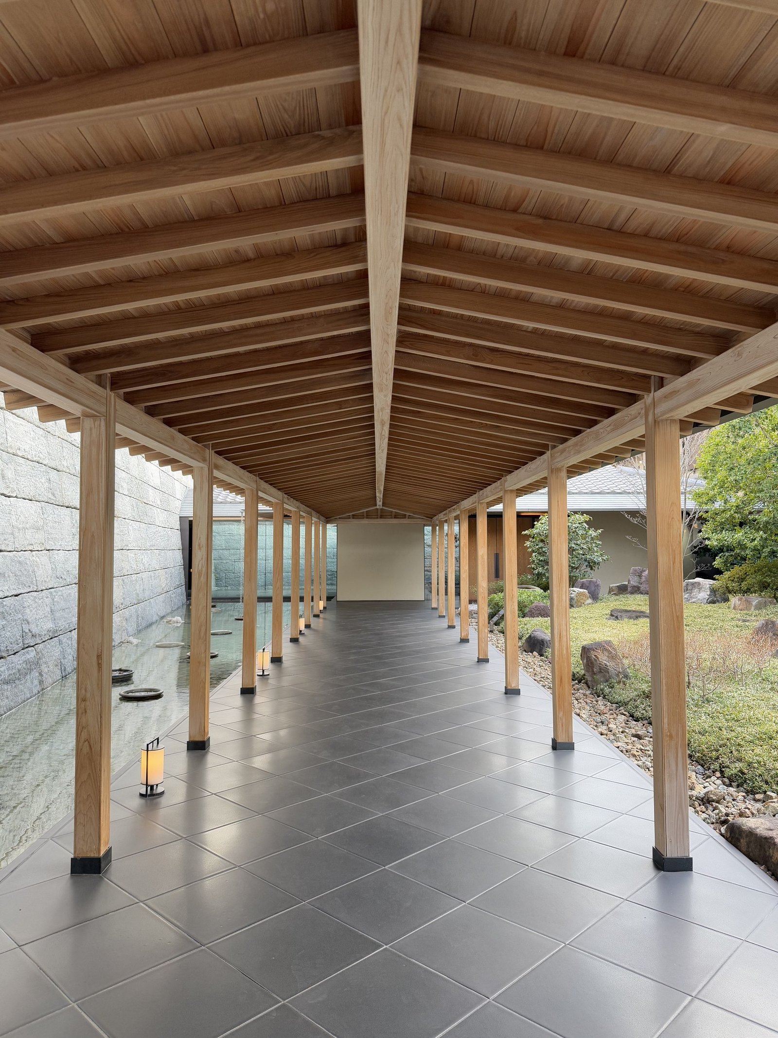 The covered walkway with its timber posts and lanterns running the length of the garden