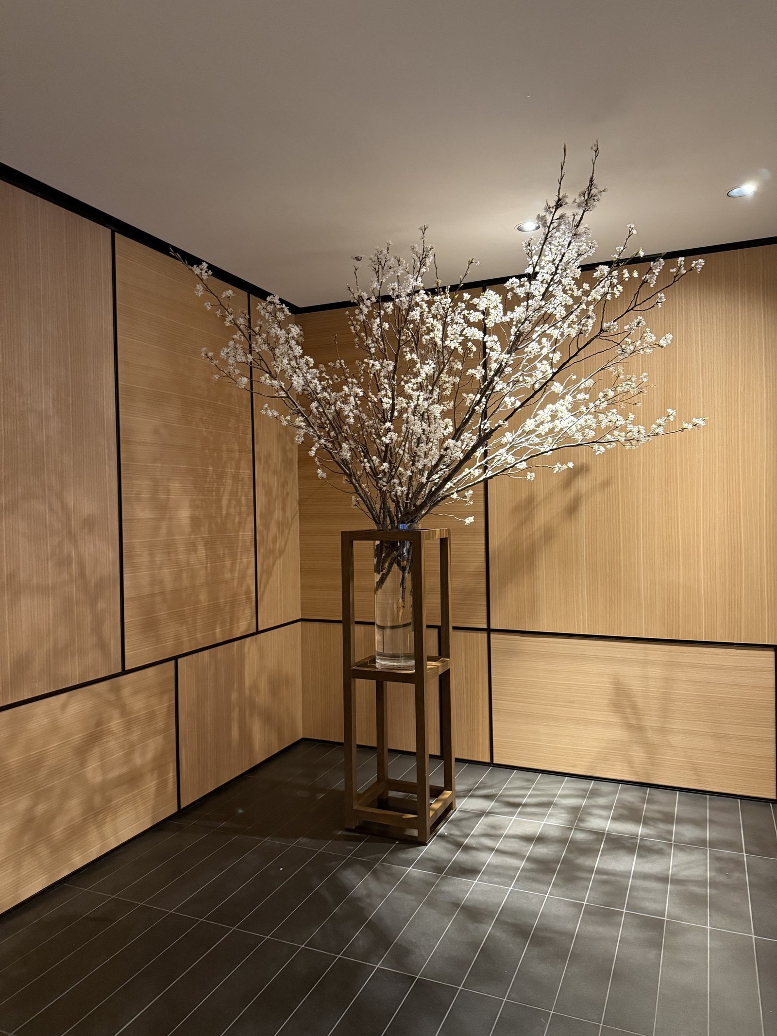 A timber corridor at the entrance with a tall branch of white blossom in a vase