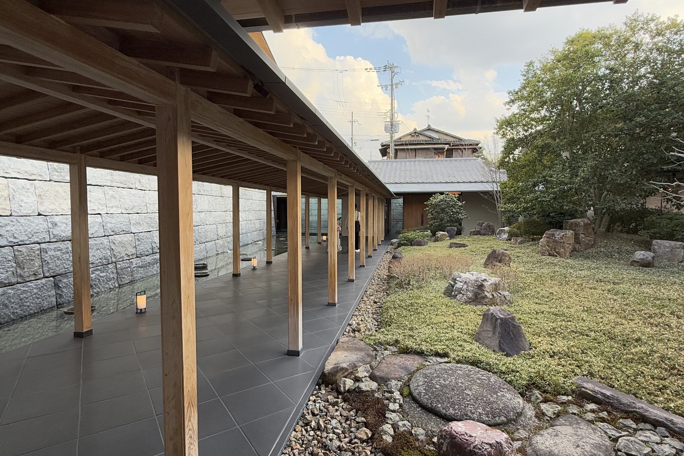 A timber colonnade at Park Hyatt Kyoto running beside a garden of stone, moss and raked gravel