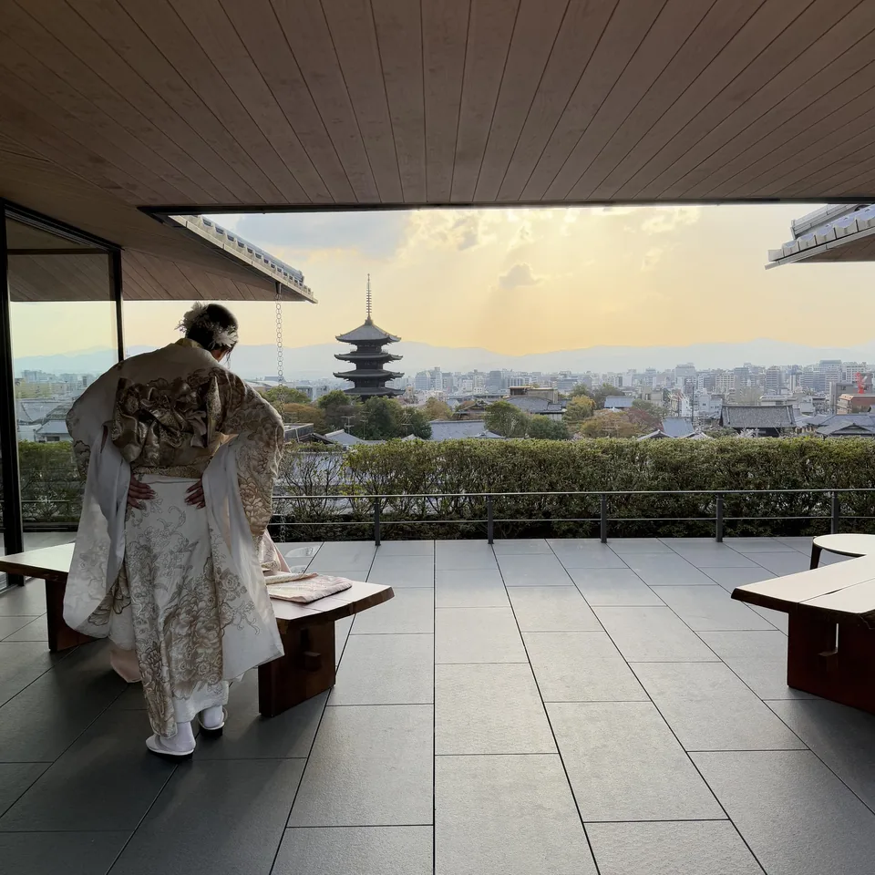 A figure in a kimono crossing the terrace with the pagoda beyond
