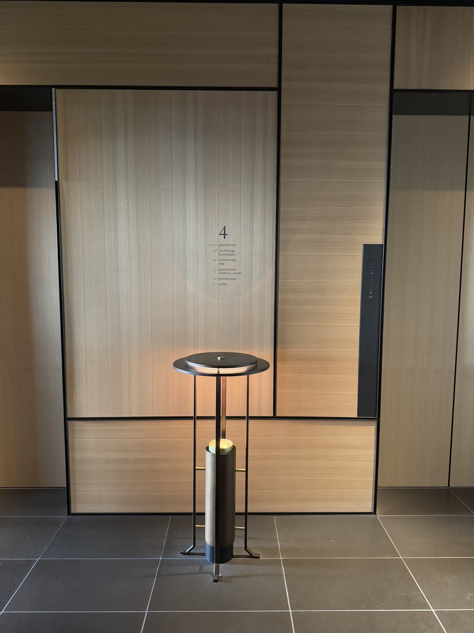 A quiet timber lobby with a single lit candle on a slim table