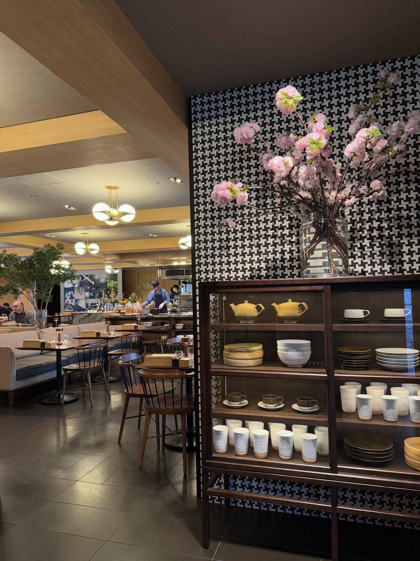 A counter of jars and pastries behind a timber lattice with a branch of magnolia on it