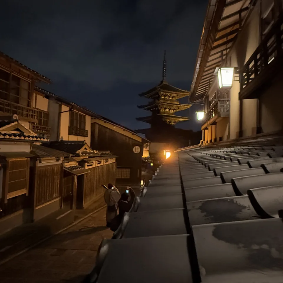A lantern-lit lane in Higashiyama at night with the pagoda above the rooftops