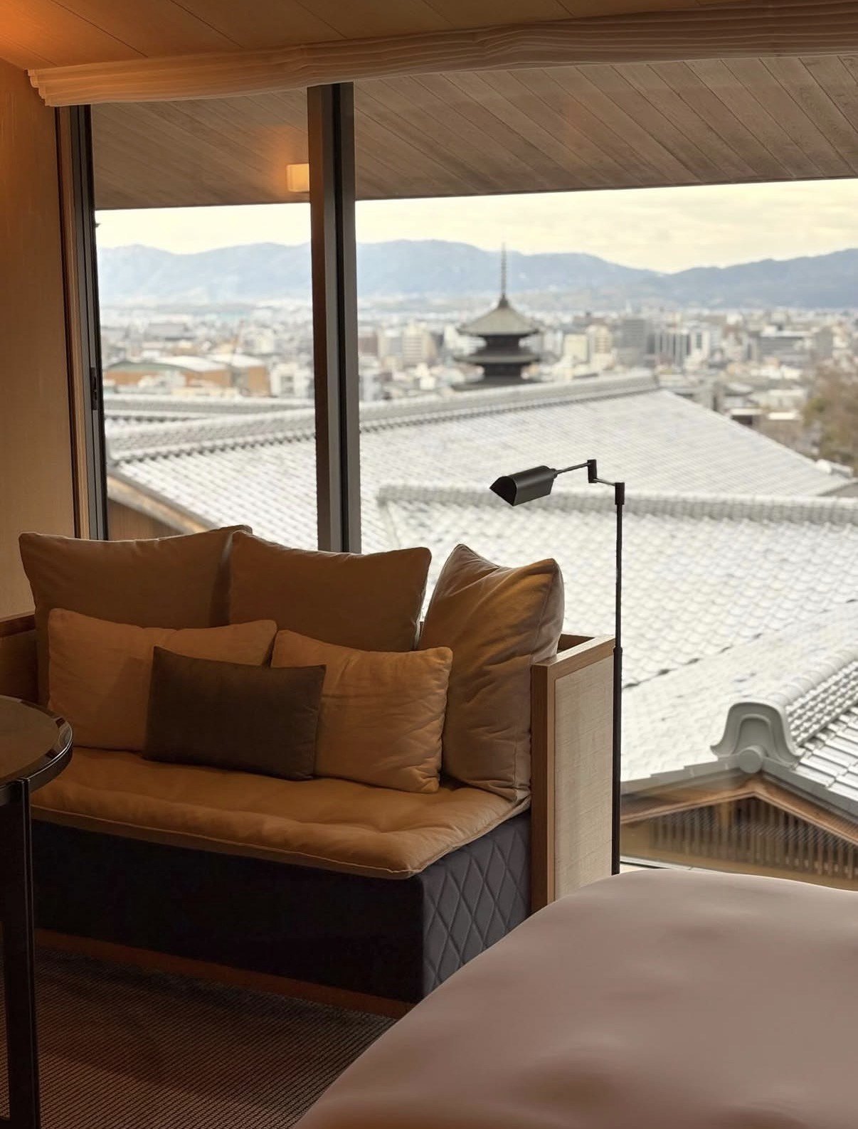 A sofa at a wide window with the Yasaka pagoda and the tiled roofs of Kyoto beyond