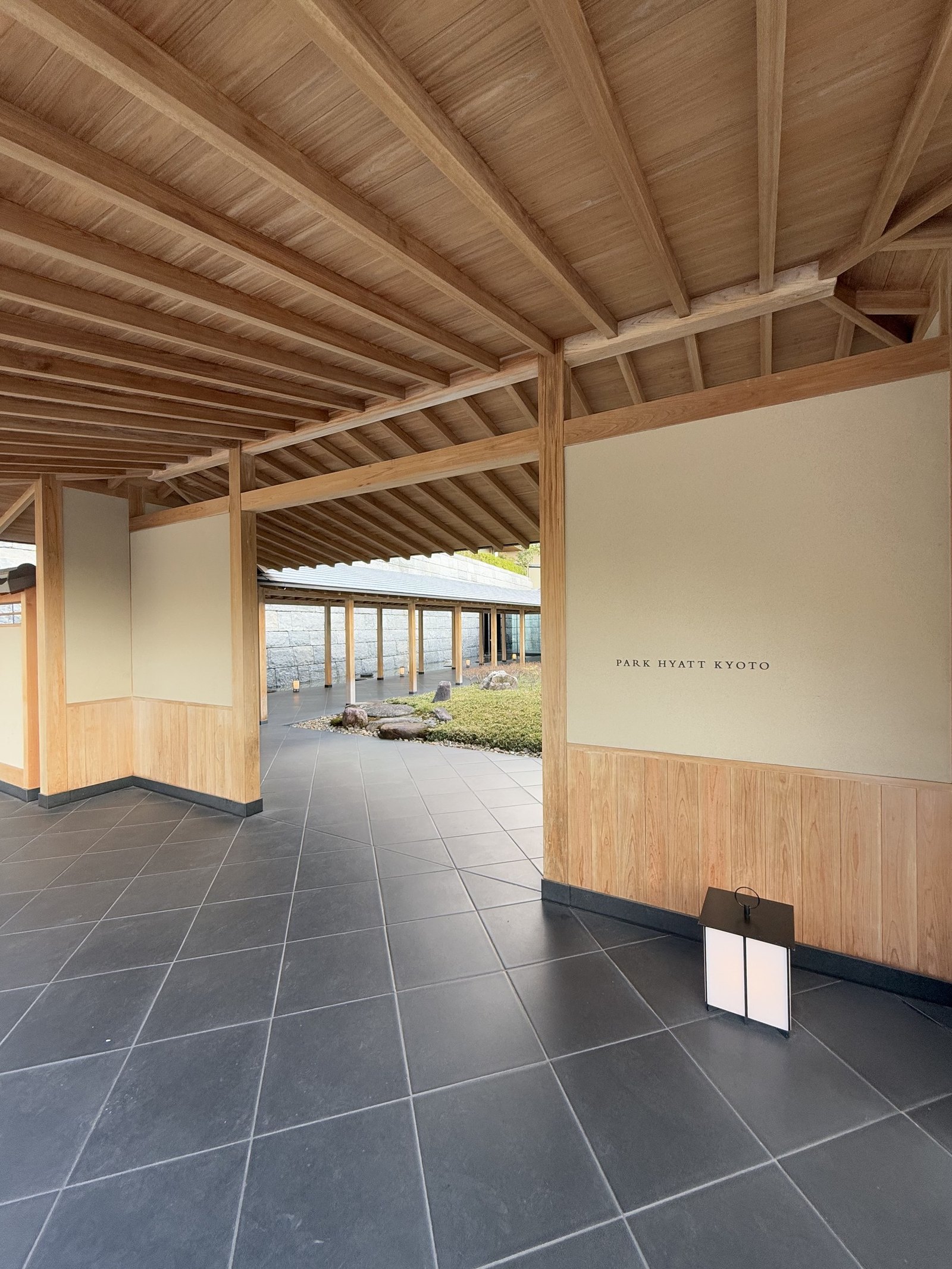 The end of the covered walkway opening onto the garden and the hotel name on the wall