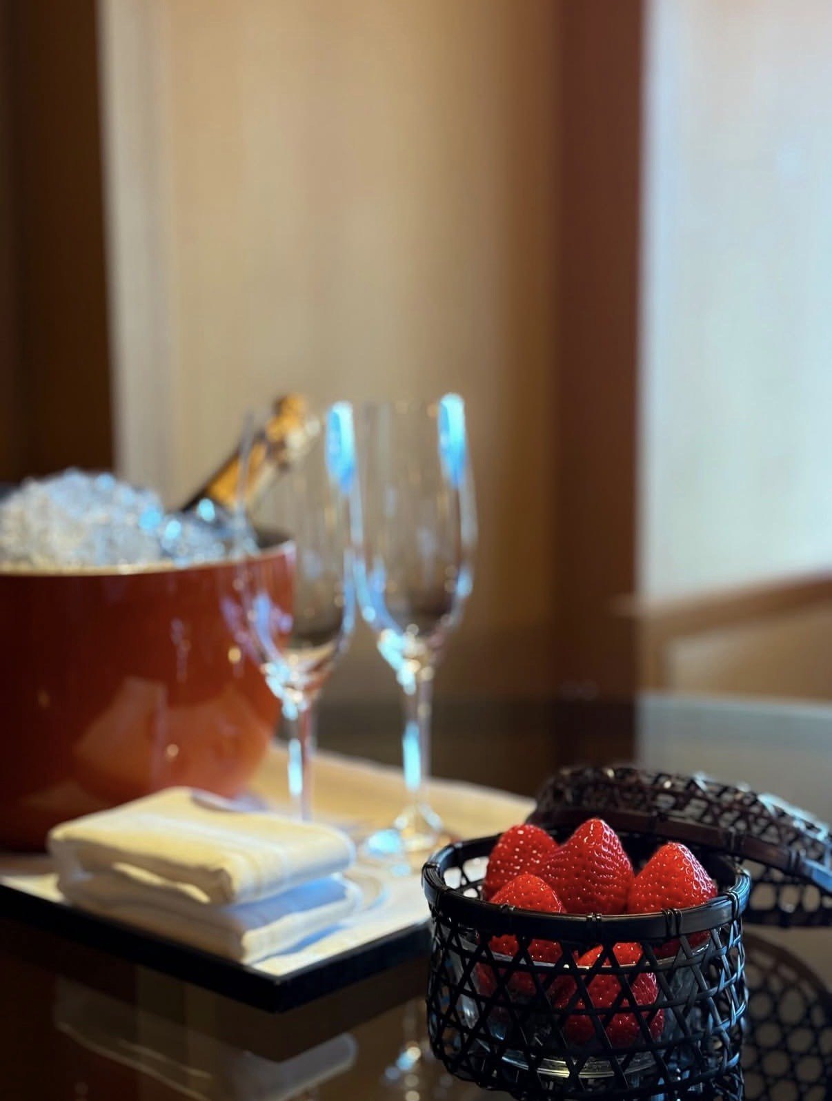 A welcome tray with champagne in ice, two glasses and a bowl of strawberries