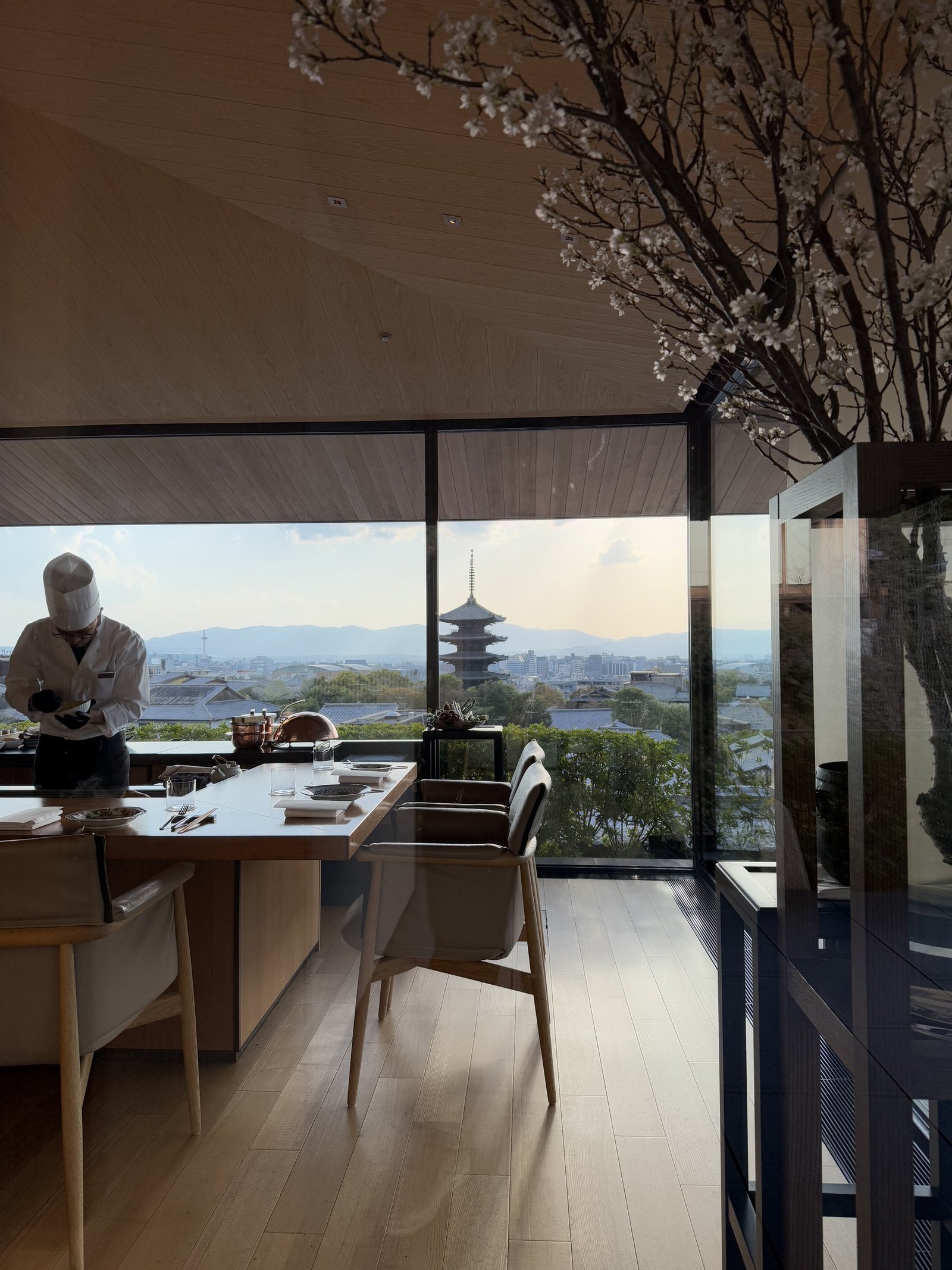 A chef working at the counter at Yasaka with the pagoda framed in the window beyond
