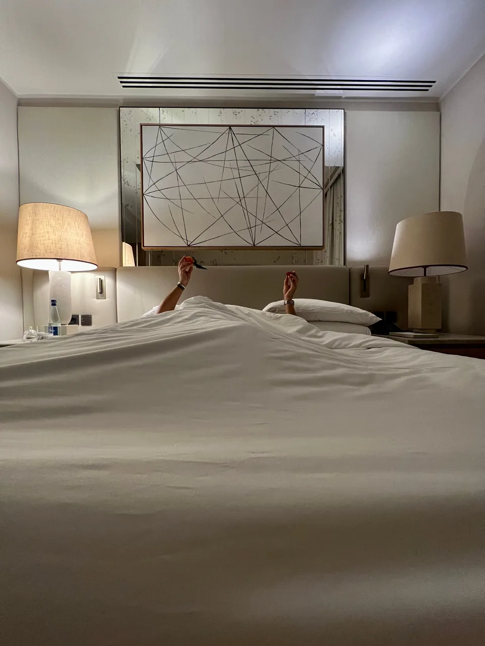 Two pairs of hands holding fruit above the duvet of a bed at Park Hyatt Milano