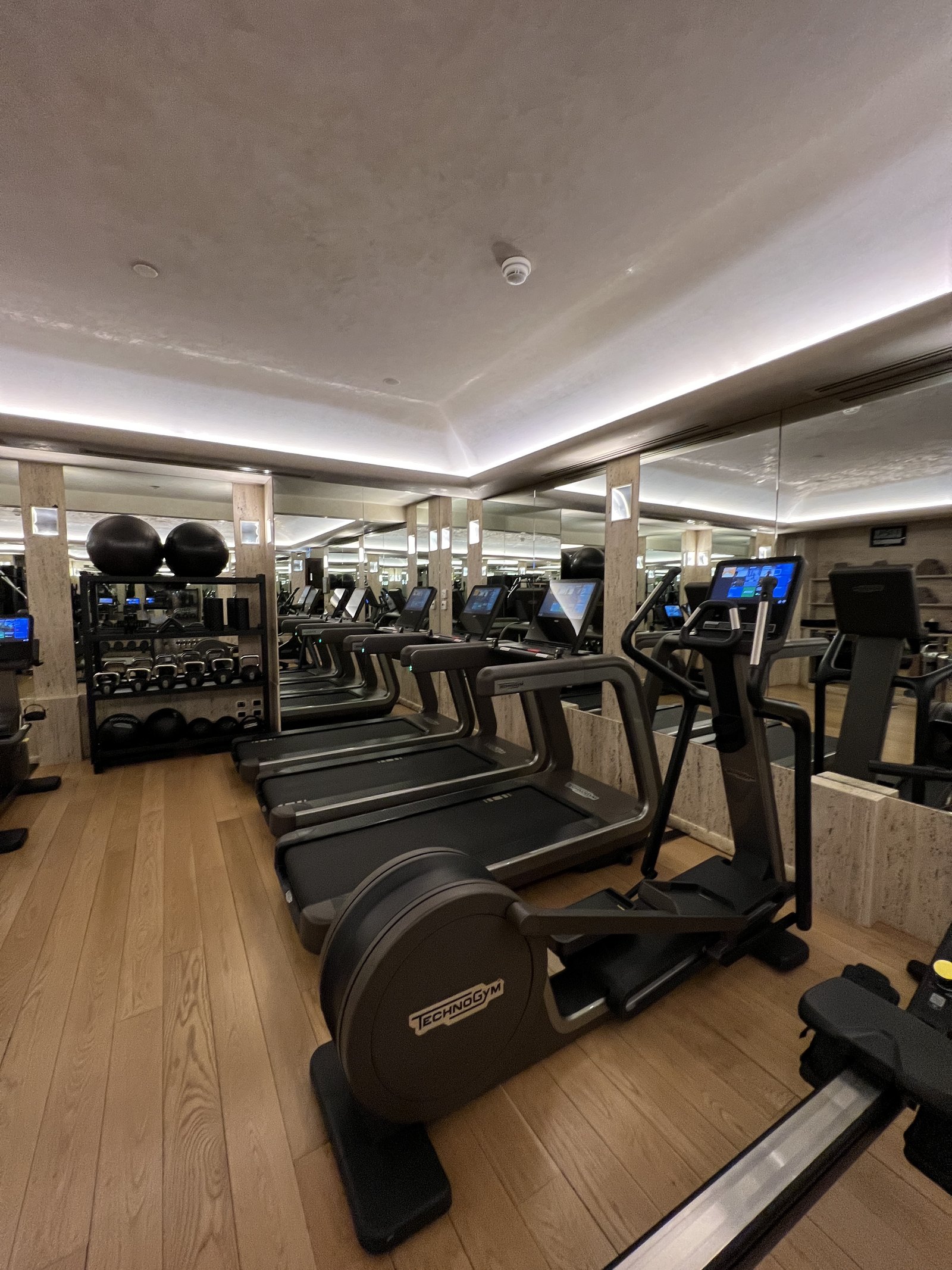 A gym with rows of treadmills and cross trainers in front of mirrors