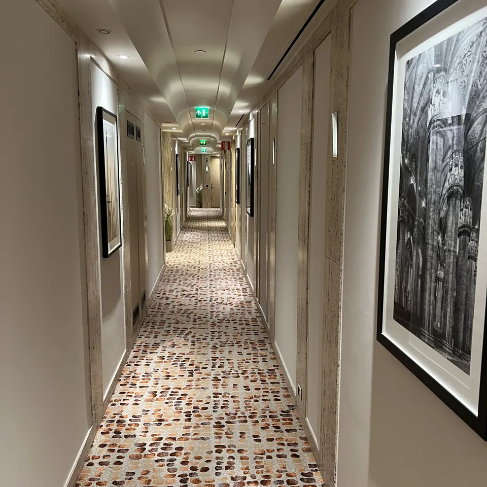 A long corridor with a pebble mosaic floor and black and white photographs on the walls