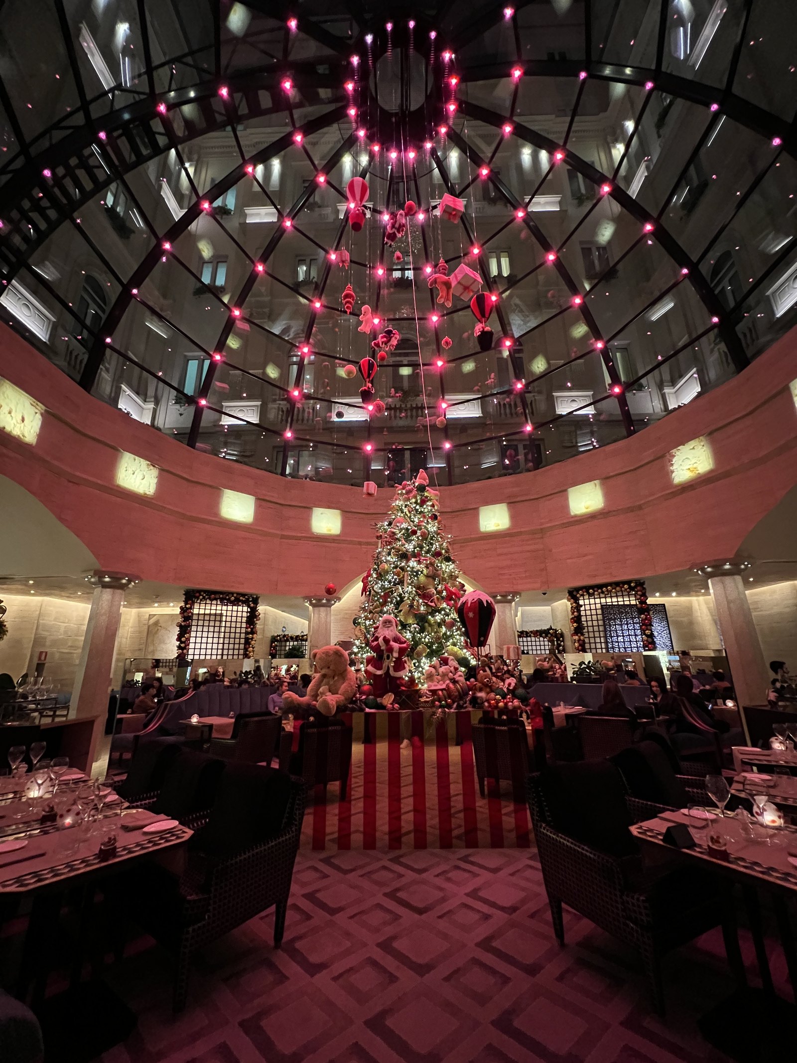 The restaurant seen from the far side, with red-lit tables and a Christmas tree beyond
